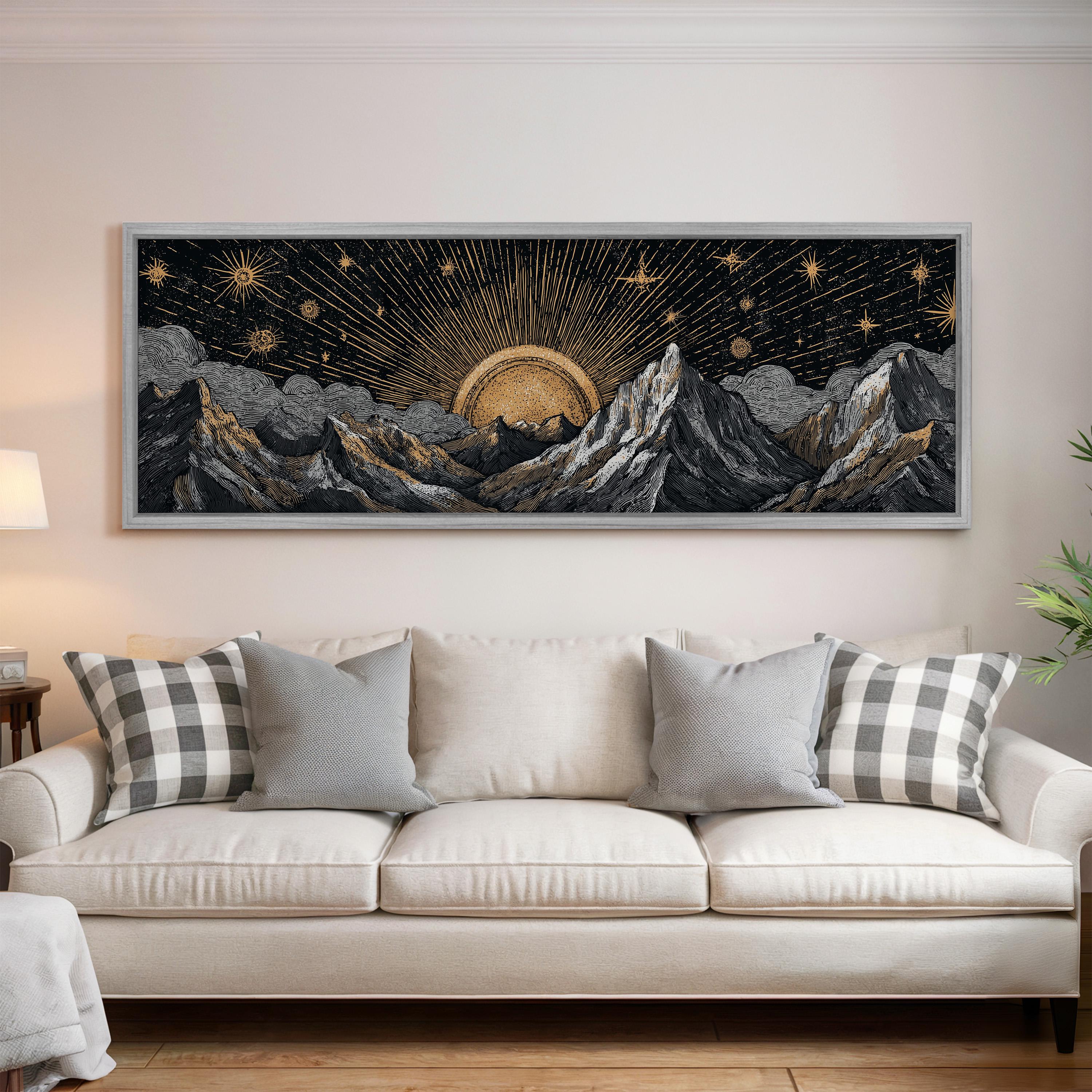 a large framed artwork depicting a night sky with mountains and a sun in the center, hanging on a wall above a white couch with decorative pillows.