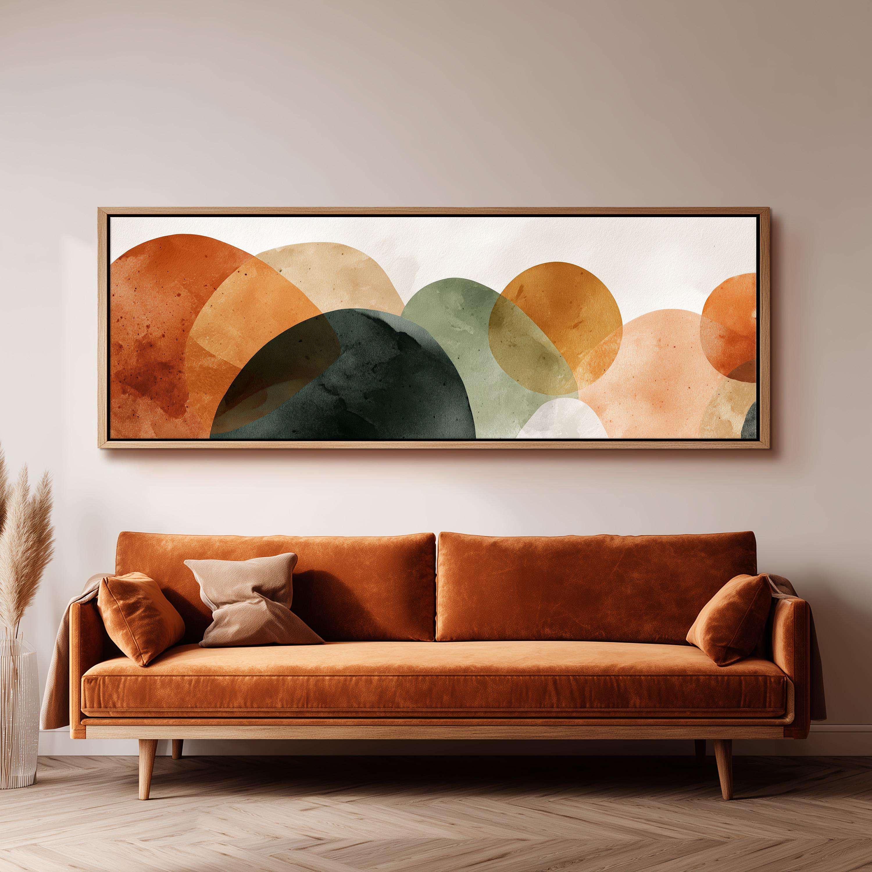 a large abstract painting hanging on a wall above a brown sofa with two pillows.