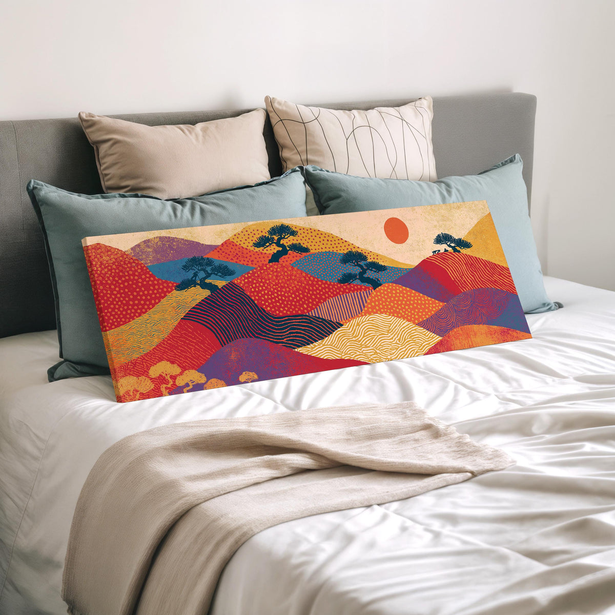Bonsai trees on patterned hills with a red sun wide panoramic canvas print laid on a bed to show its size