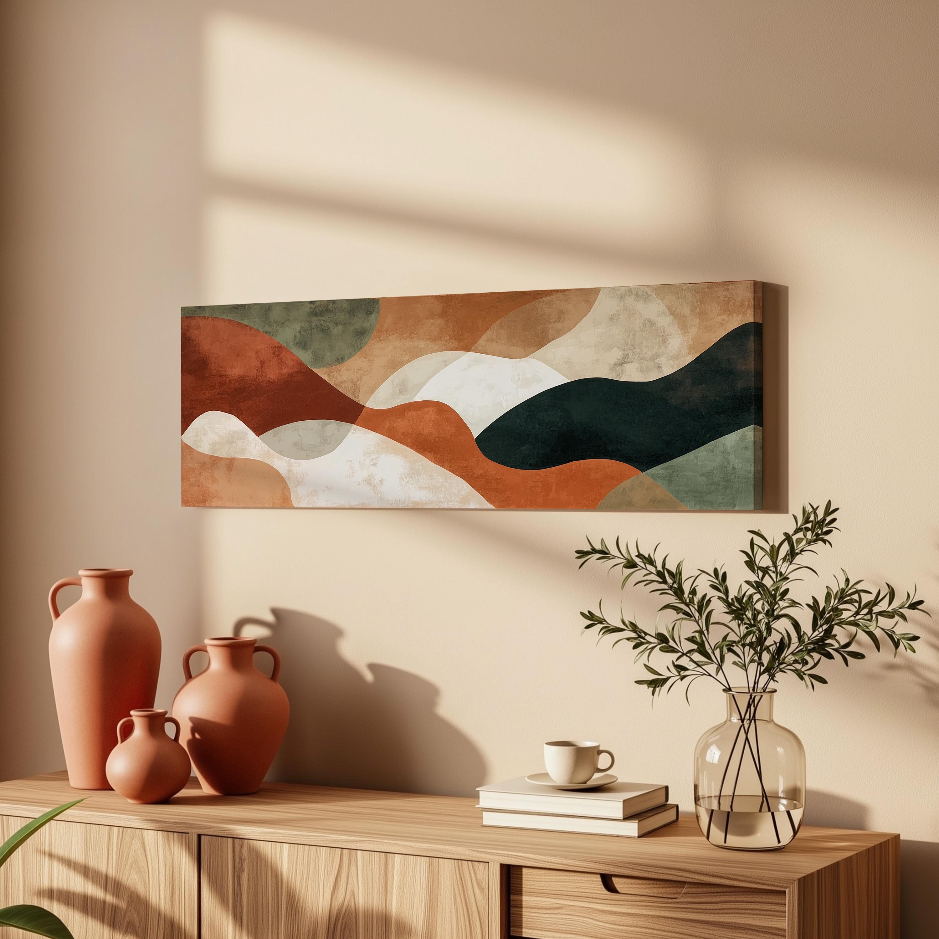 a wooden cabinet with a vase of greenery, a coffee cup, and a stack of books on top. Above the cabinet, there is a large abstract painting hanging on the wall.