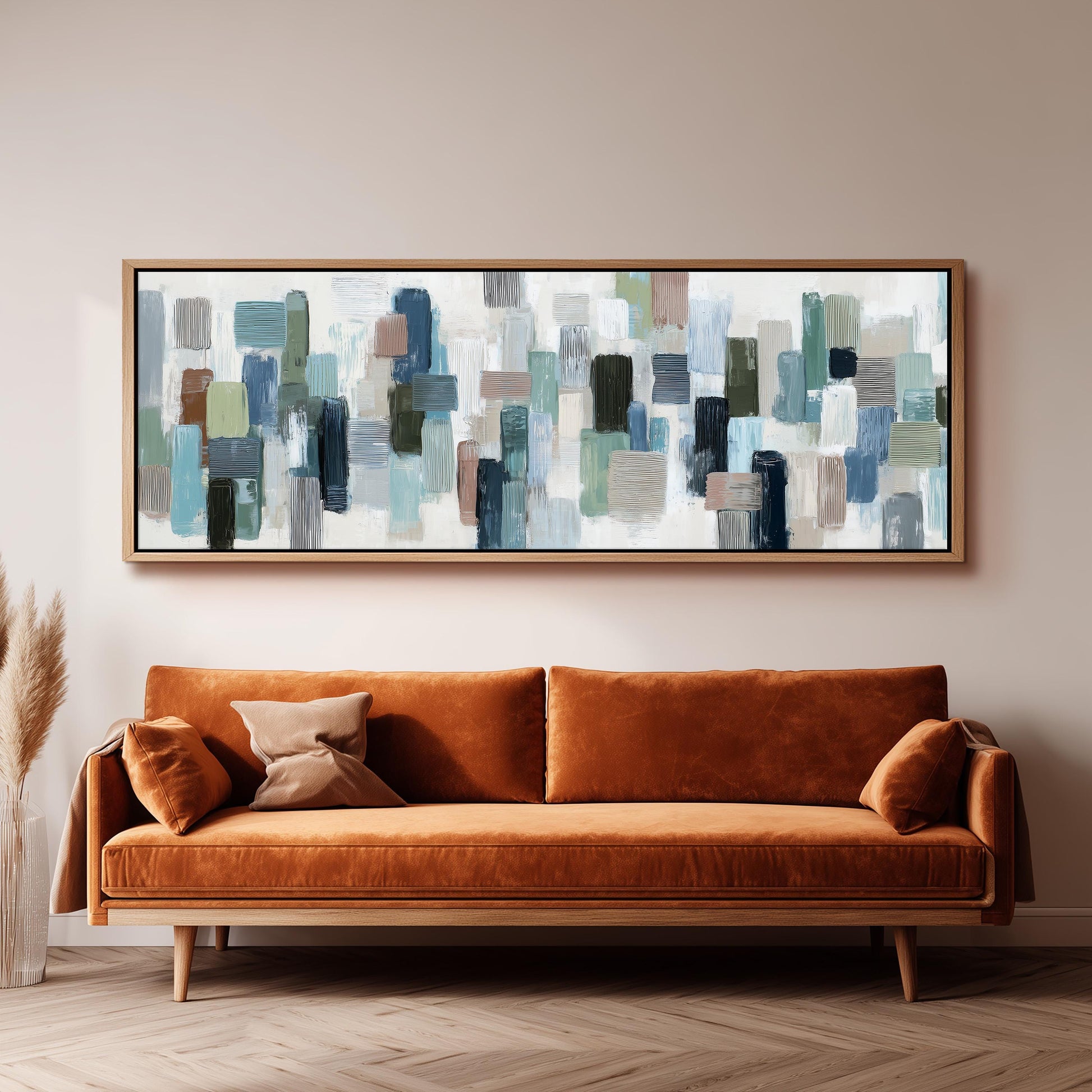 a large abstract painting hanging on a wall above a brown sofa with orange cushions.