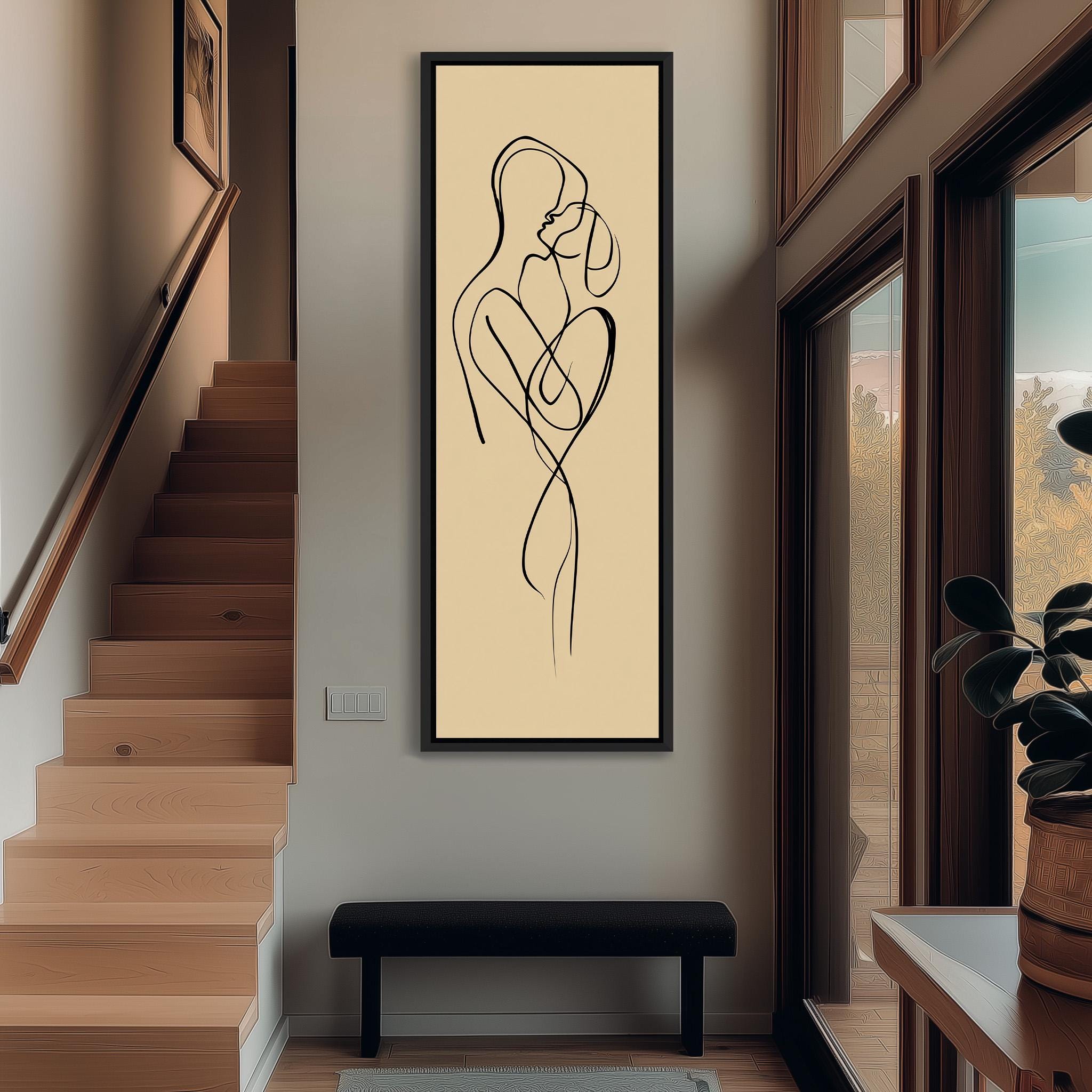 a minimalist art piece depicting a man and a woman embracing, hanging on a wall in a hallway.