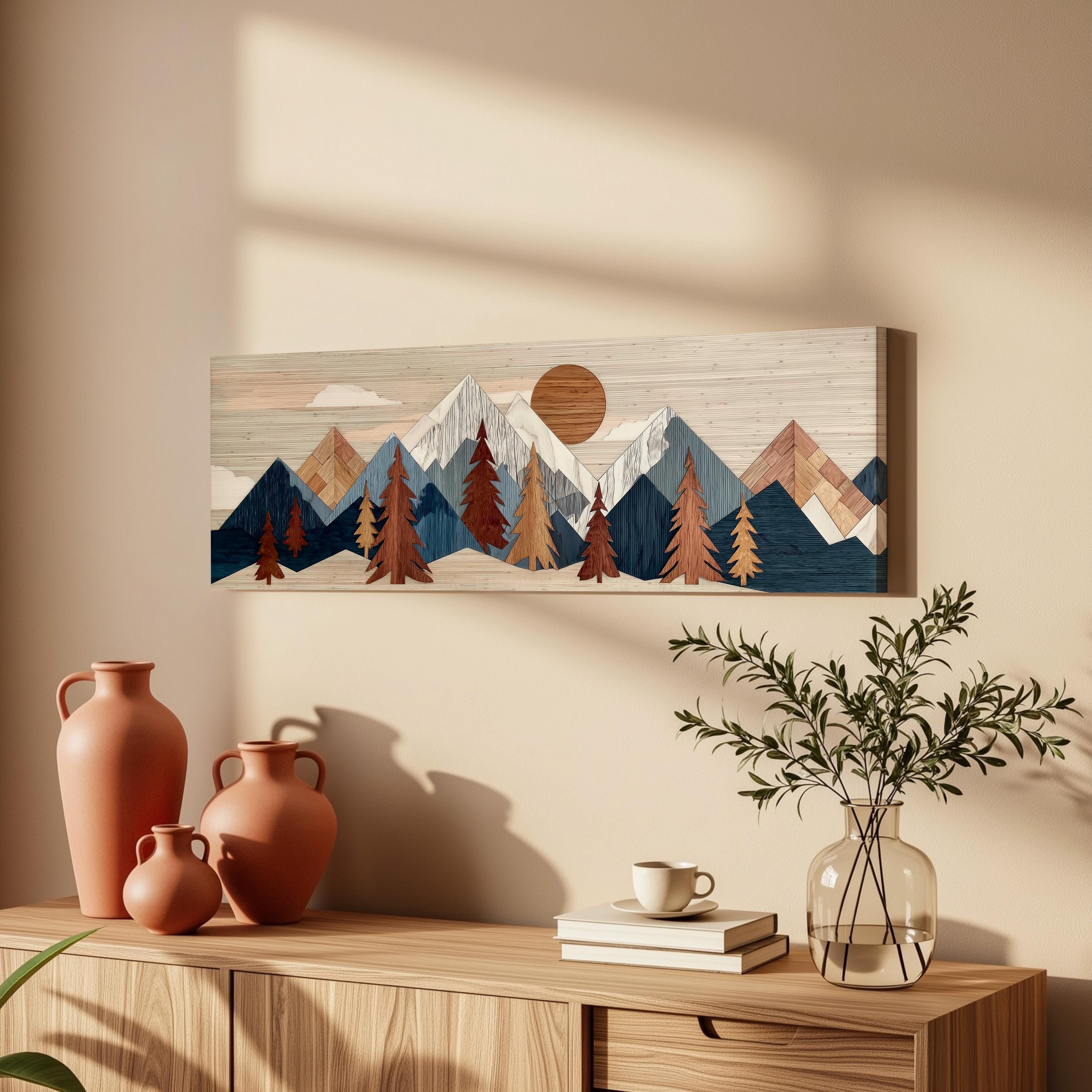 a wooden cabinet with a vase of greenery, a stack of books, and a ceramic vase on top. Above the cabinet, there is a framed artwork depicting a mountain landscape with a sun and clouds.