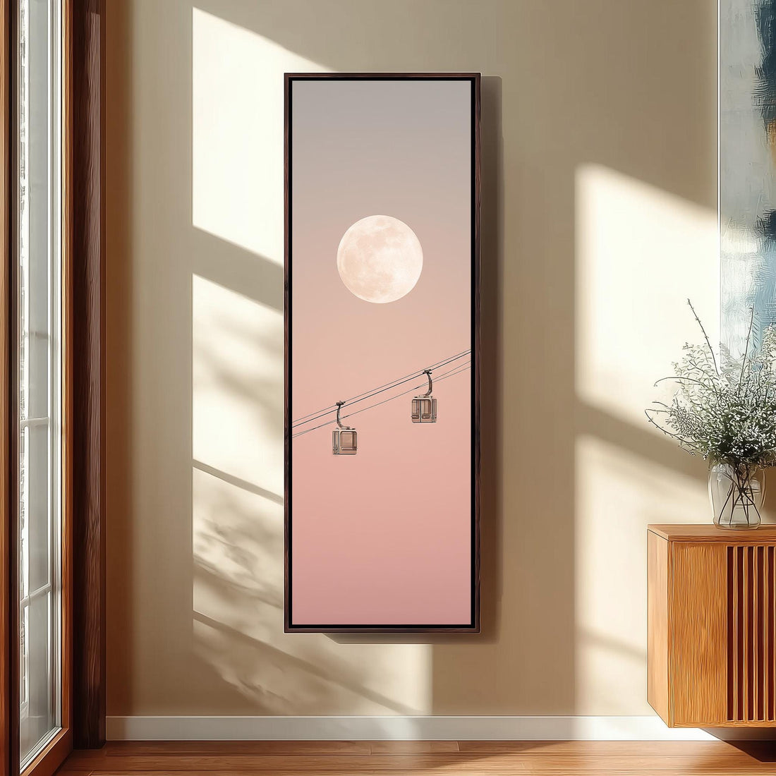 a large framed artwork hanging on a wall, depicting a serene scene with a full moon and two hanging lanterns.