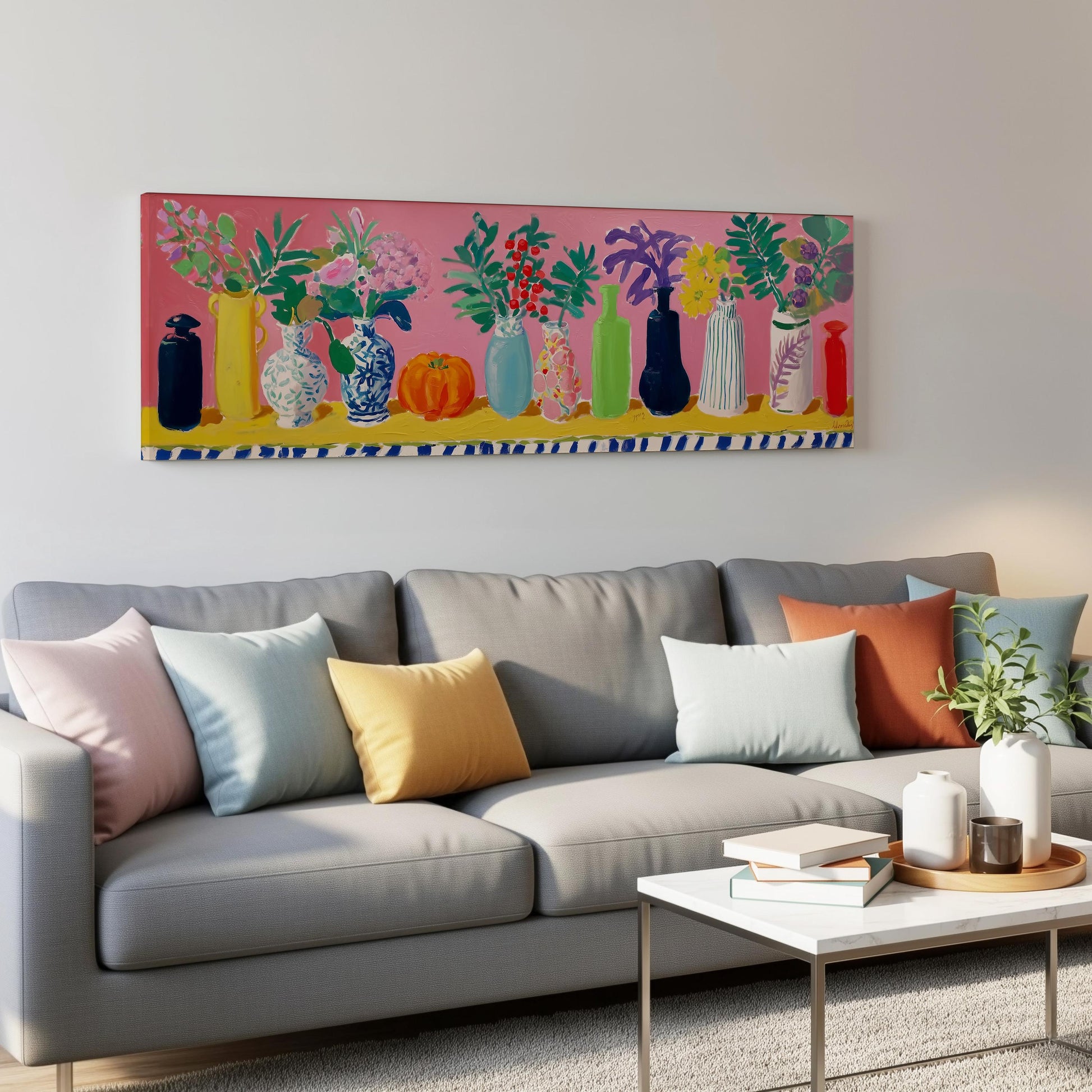 a living room with a gray sofa adorned with colorful throw pillows. Above the sofa, there is a large painting depicting a row of vases filled with flowers in various colors and shapes. The painting is hanging on a white wall, creating a visually appealing contrast with the gray sofa.