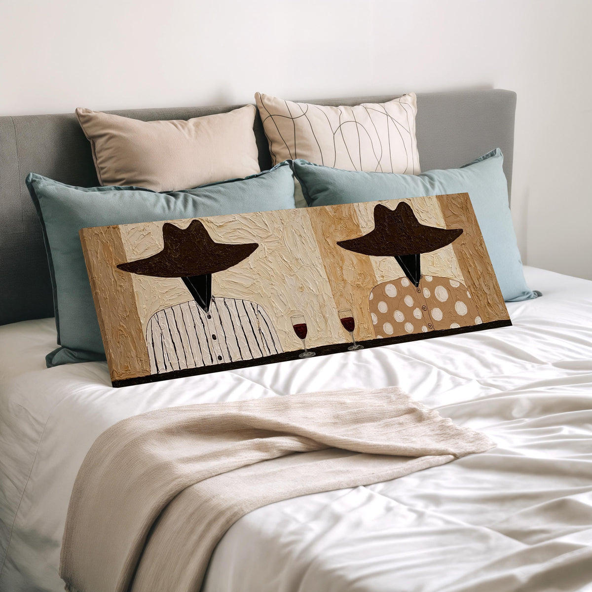 Two folk figures in hats toasting with red wine wide panoramic canvas print laid on a bed to show its size