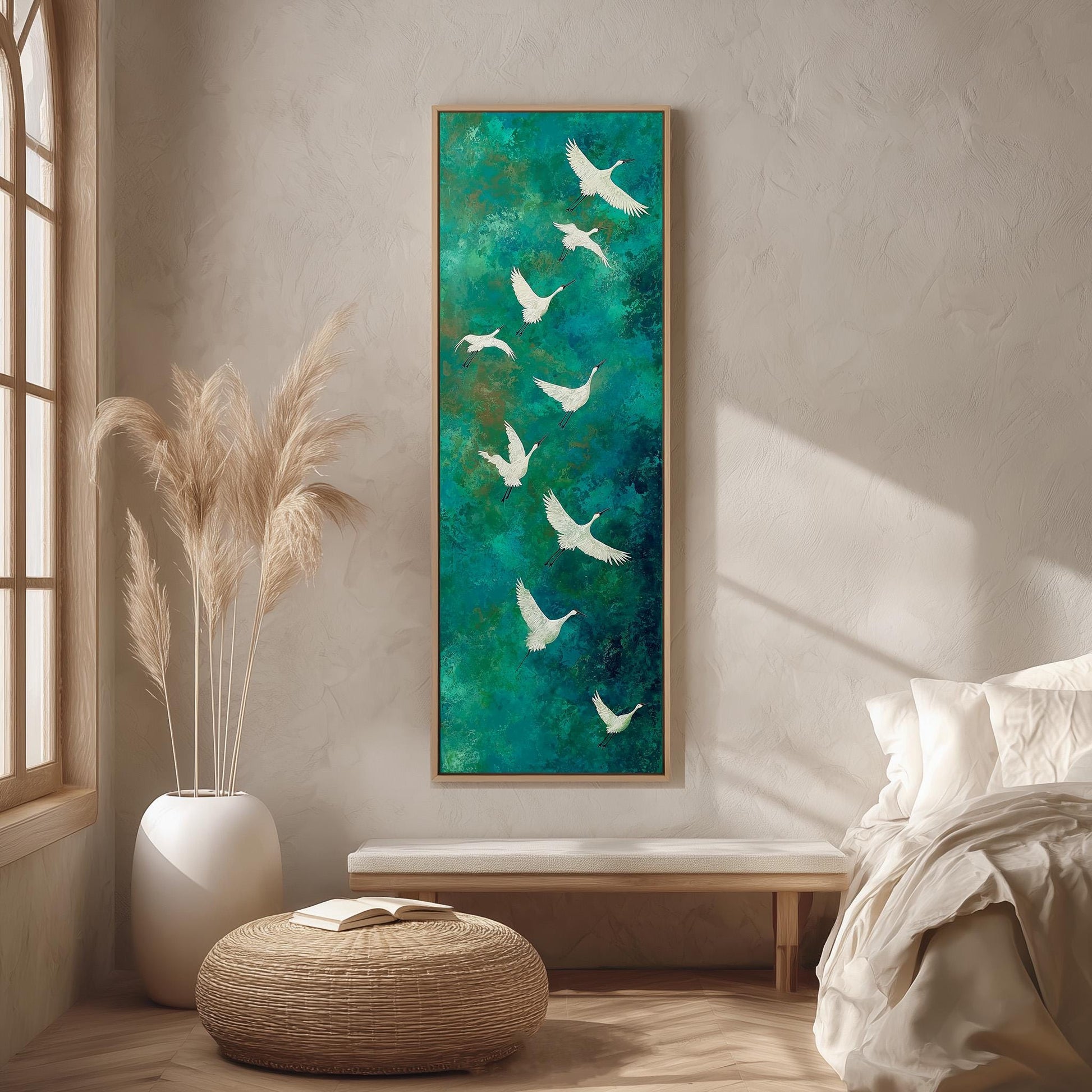 a large painting of white birds flying over a green background, hanging on a wall in a room with a bed, a wicker ottoman, and a potted plant.