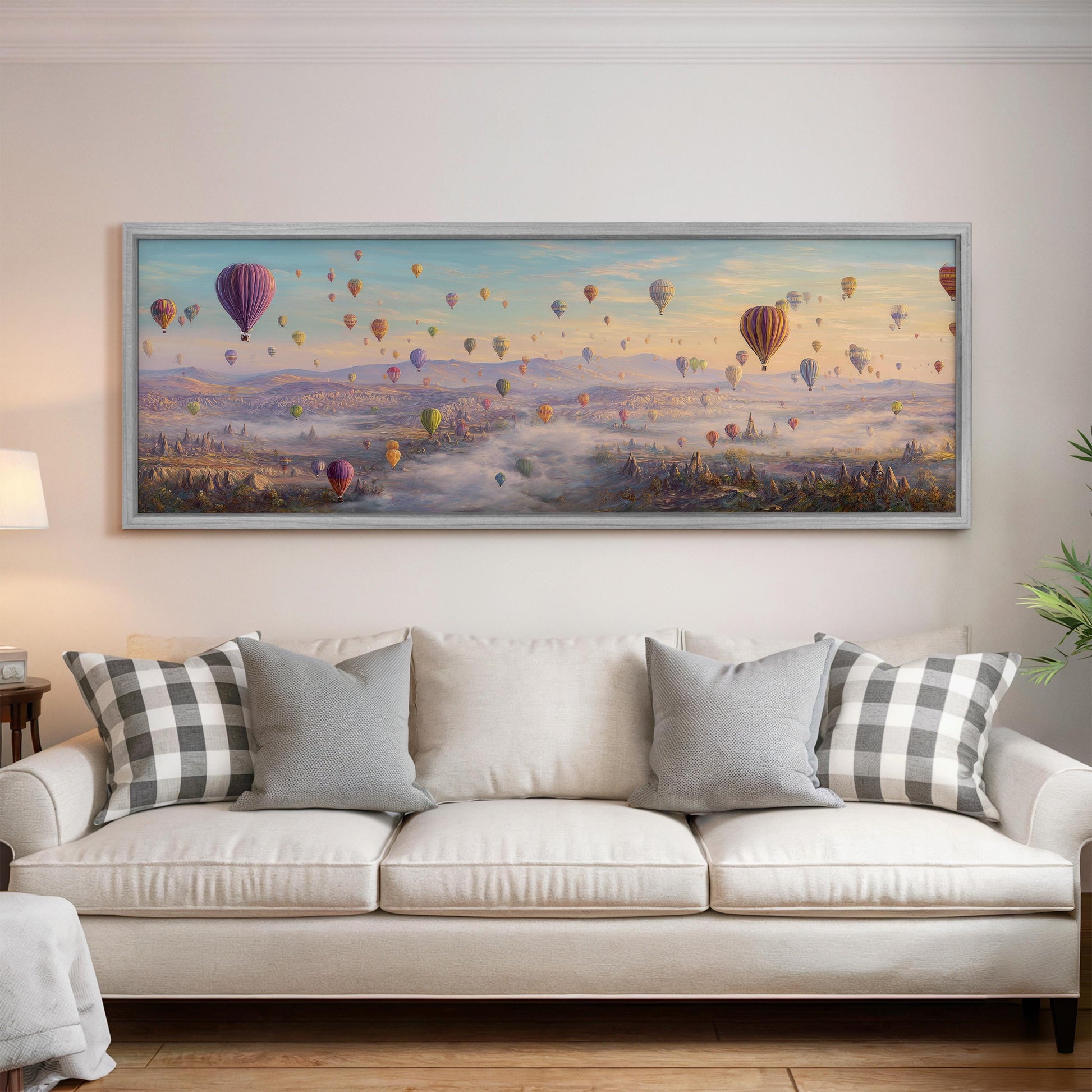 a large painting of hot air balloons floating in the sky above a cityscape, hanging on a wall above a white couch with patterned throw pillows.