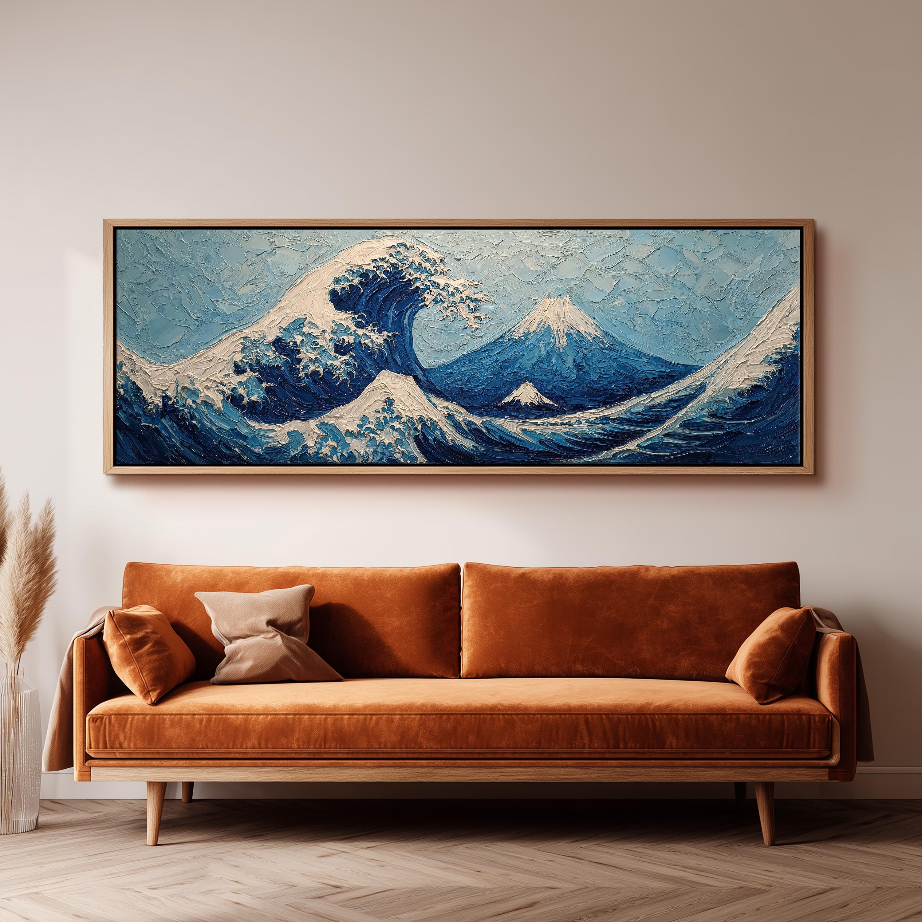 a large, framed painting of a wave with mountains in the background, hanging on a wall above a brown sofa.