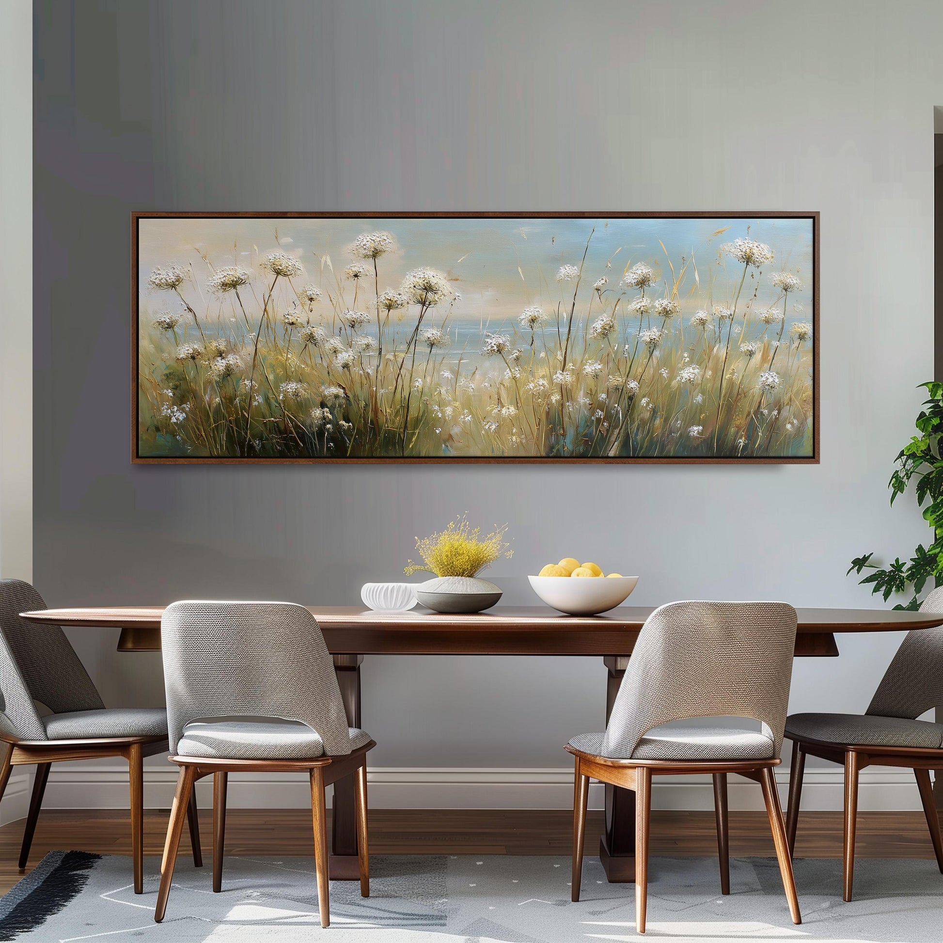 a dining room with a large painting of a field of flowers hanging on the wall above a wooden dining table with four chairs. The table is set with a bowl of fruit and a vase of flowers, creating a cozy and inviting atmosphere.