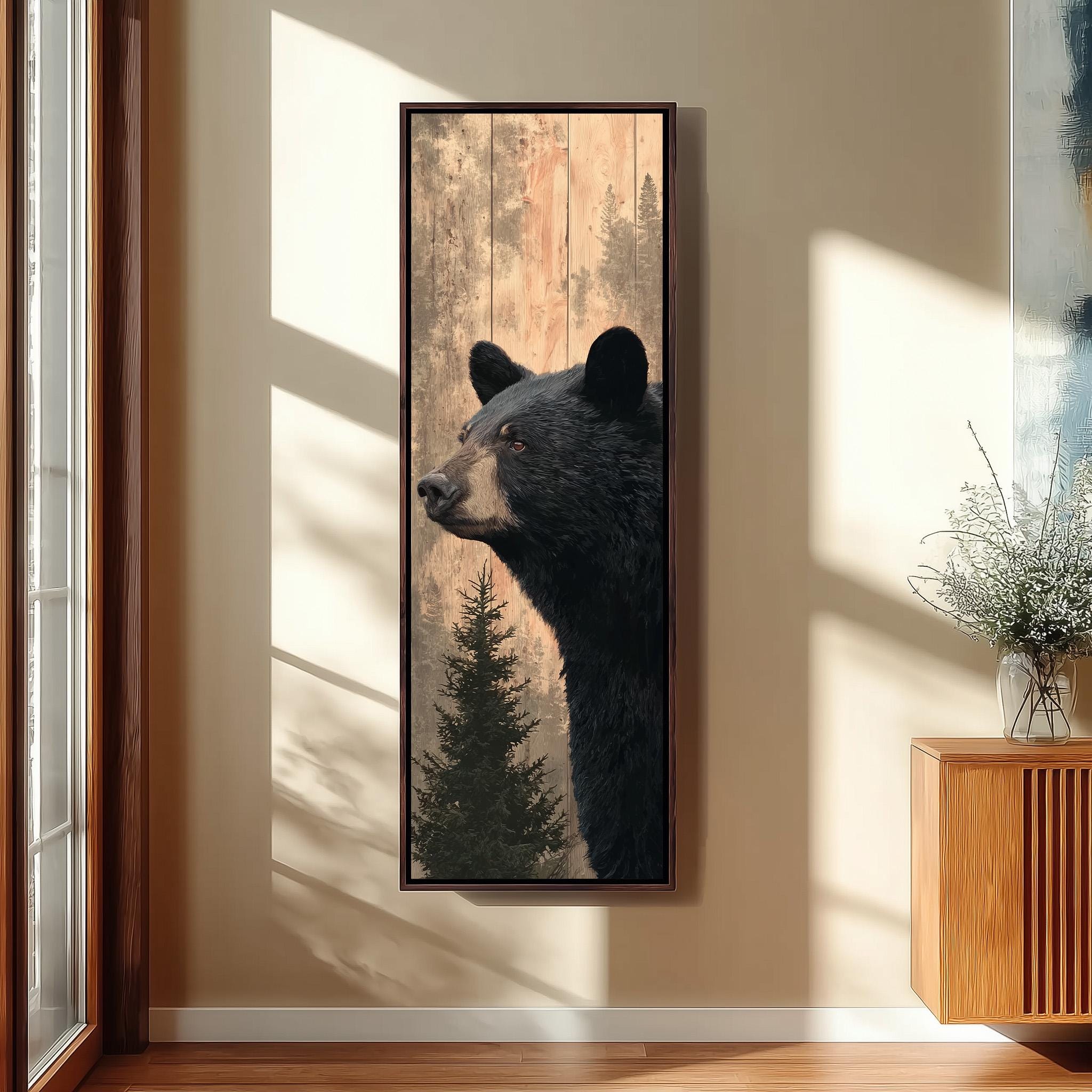 a large framed painting of a black bear, hanging on a wall in a room with a wooden floor and a window.