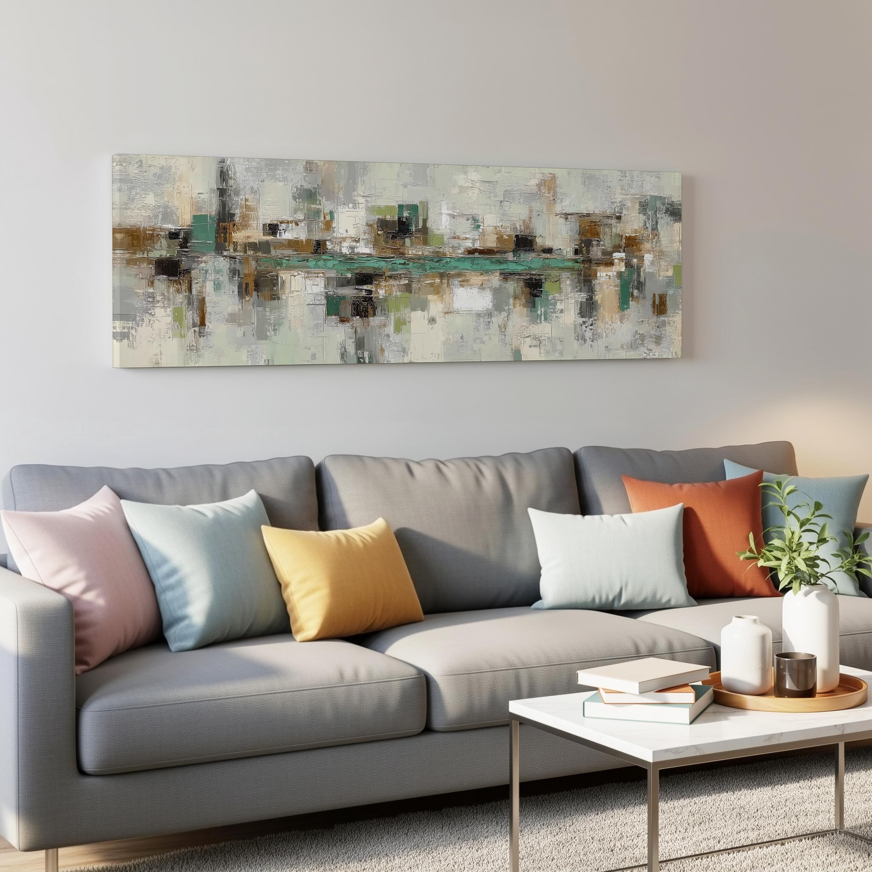 a modern living room with a gray sofa adorned with colorful throw pillows. Above the sofa, there is a large abstract painting hanging on the wall. In front of the sofa, there is a white coffee table with a stack of books and a small plant.