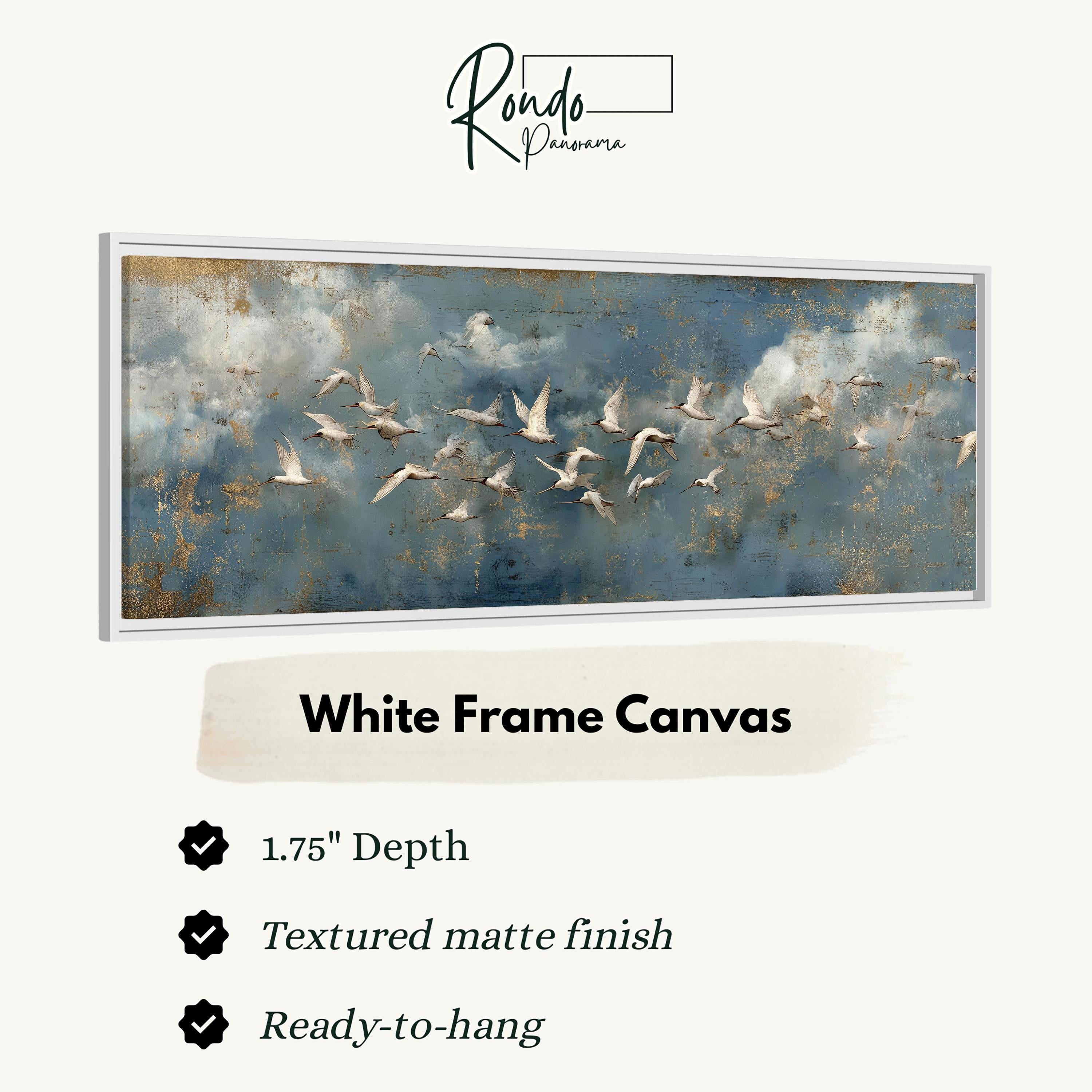 a white frame canvas with a painting of a flock of birds flying across a cloudy sky.