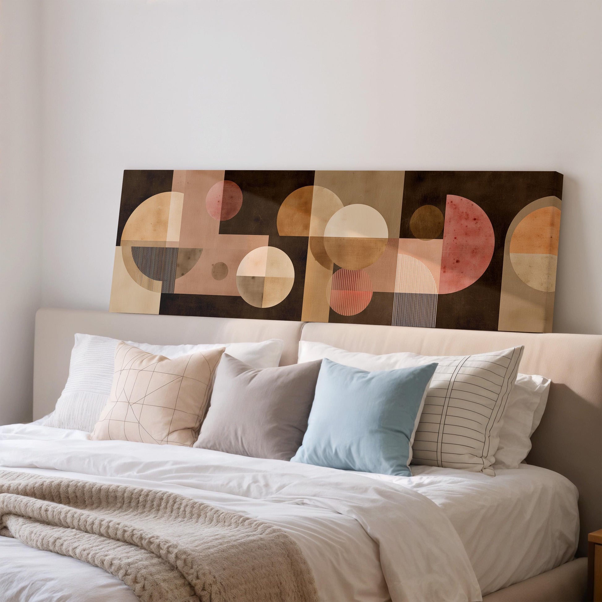 a large abstract painting hanging on a wall above a bed with white pillows and a gray blanket.