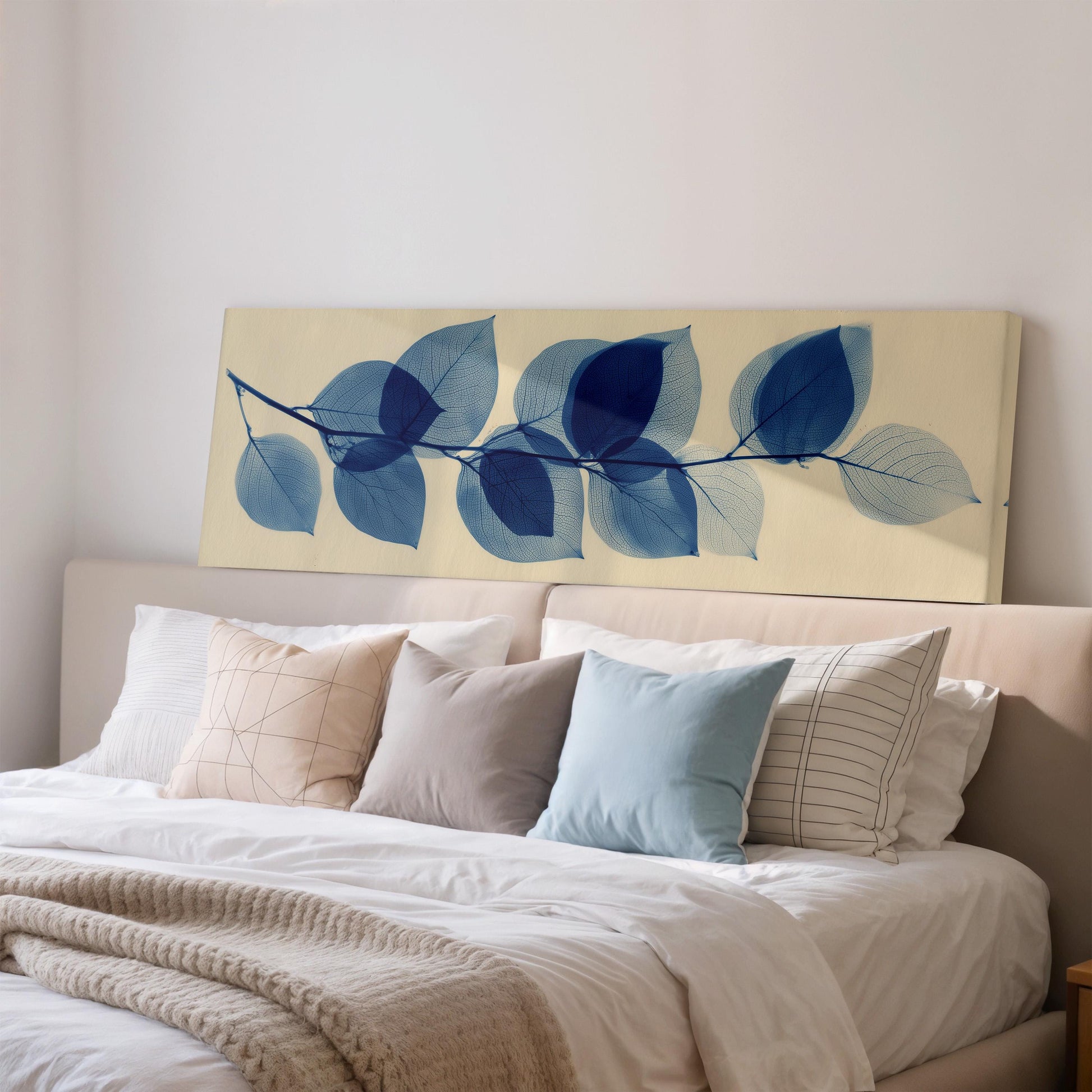 a bedroom with a bed covered in white sheets and pillows, and a large wall art piece featuring blue leaf patterns above the bed.