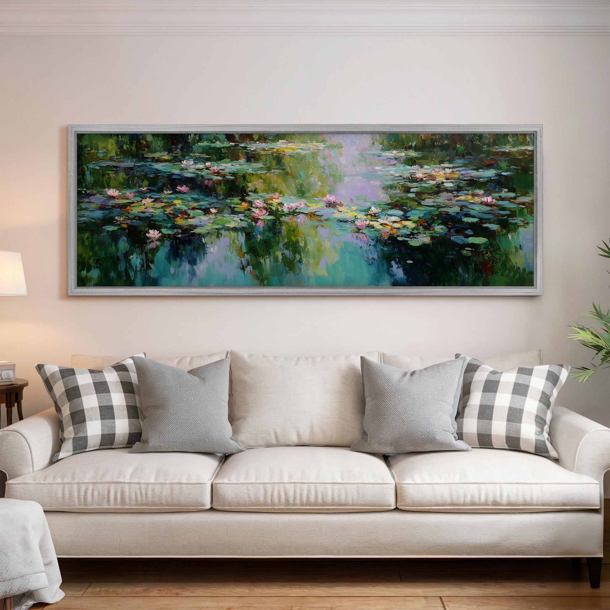 a large painting of a pond with lily pads hanging on a wall above a white sofa with gray and white patterned pillows.