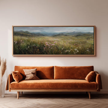 a large, framed painting of a field with flowers hanging on a wall above a brown sofa.