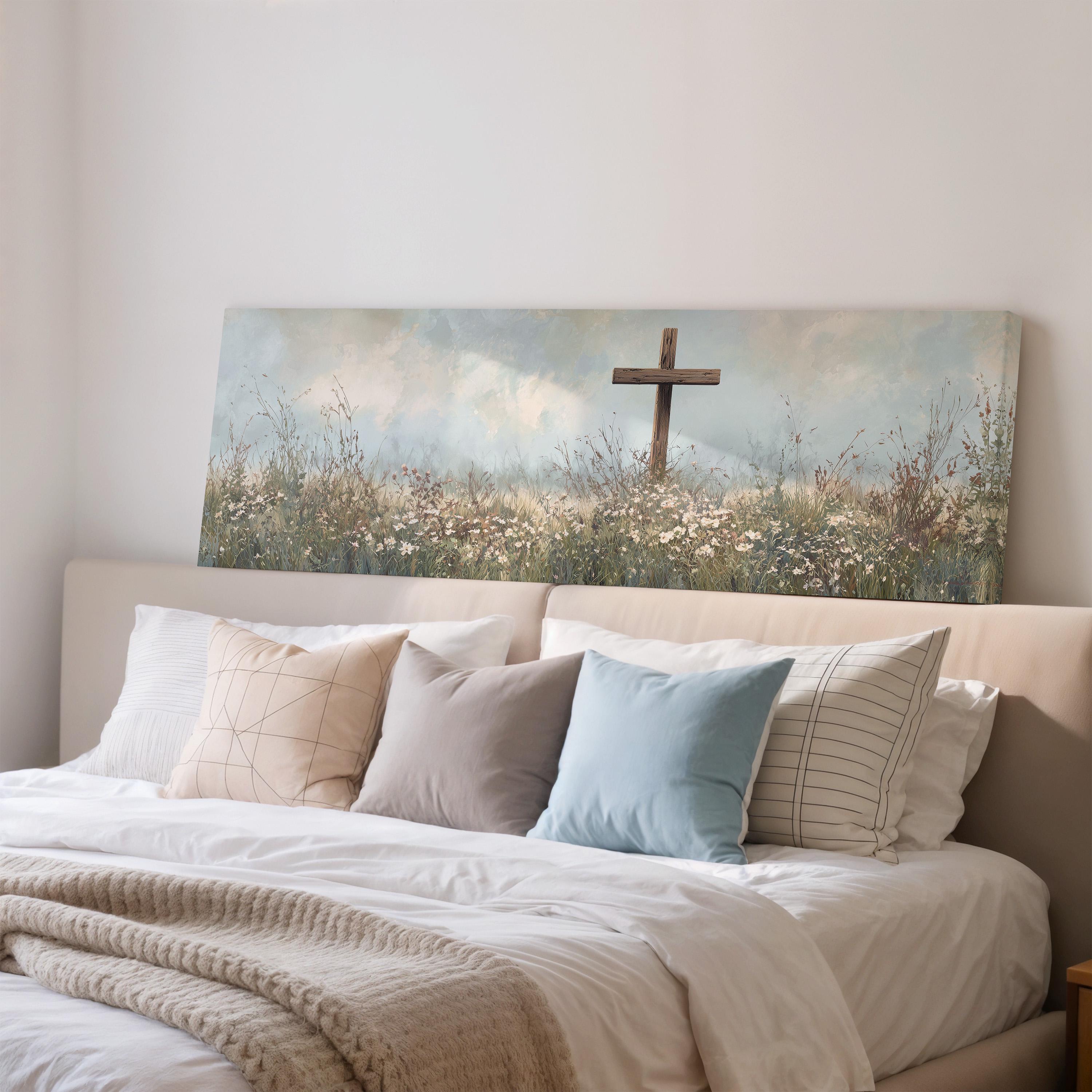 a large painting of a cross in a field of flowers hanging above a bed with white sheets and pillows.