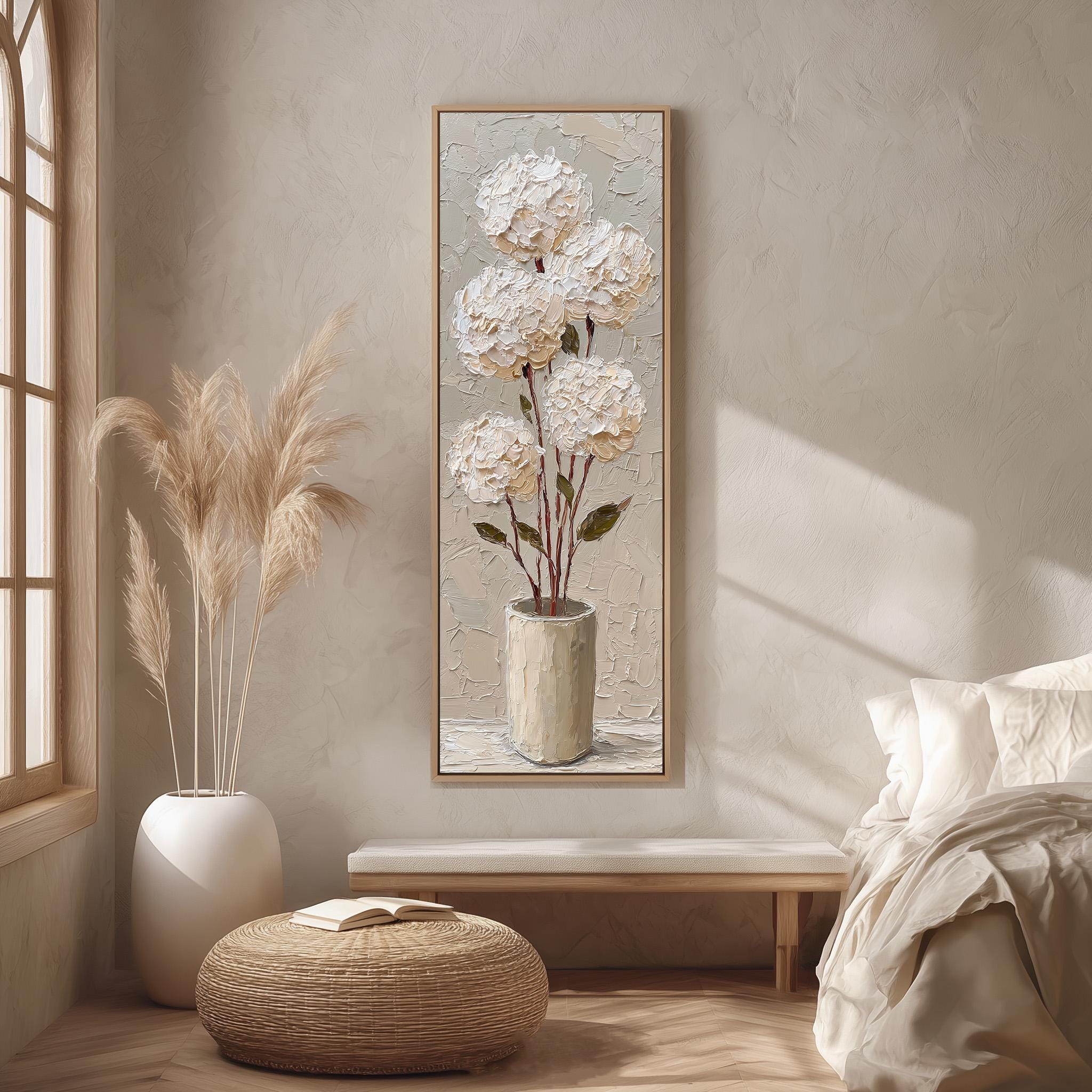 a serene and cozy bedroom scene, featuring a large painting of white flowers in a vase hanging on the wall, a white bed with a white pillow, a white wicker ottoman, and a large window with white curtains.
