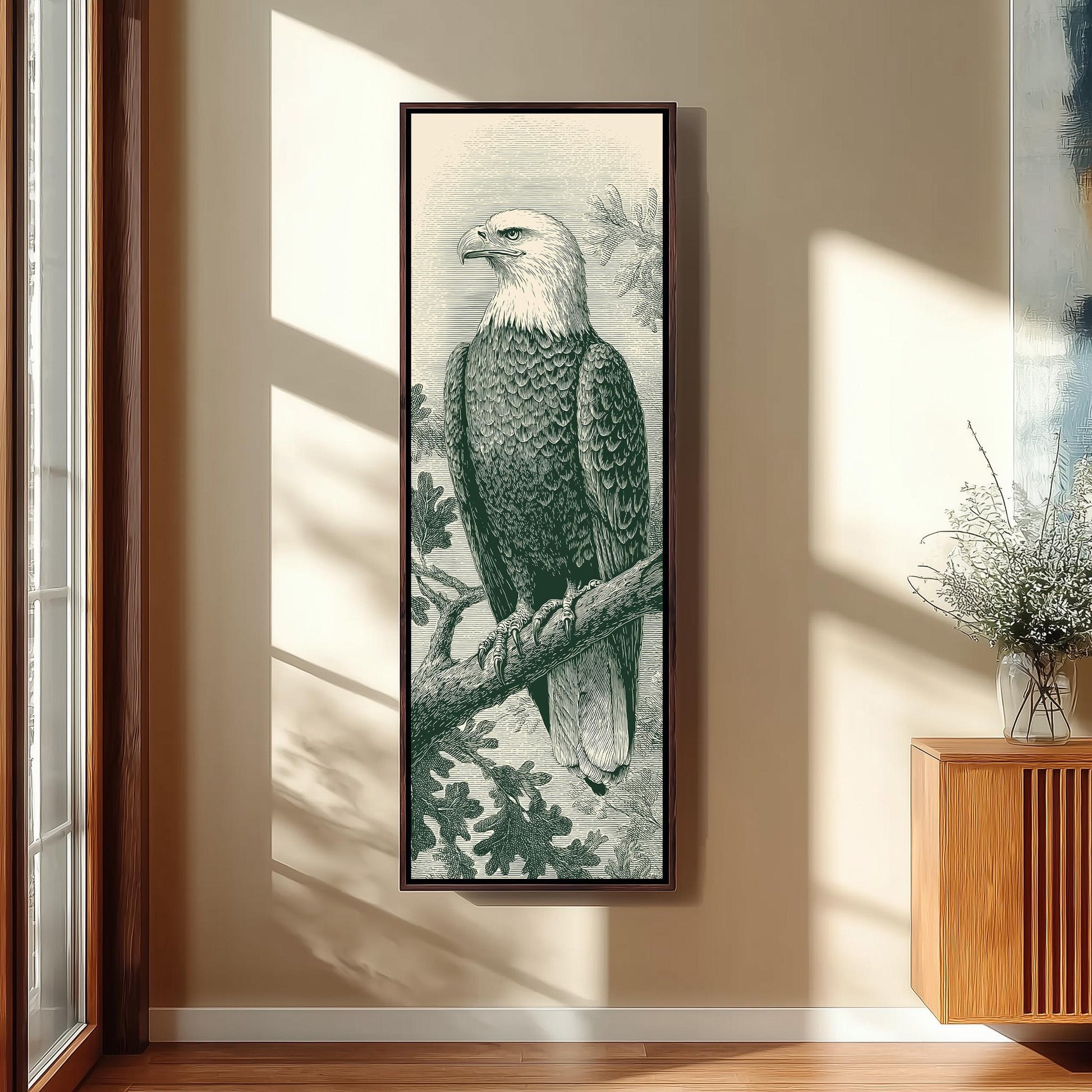 a framed illustration of a bald eagle perched on a branch, with a wooden cabinet and a vase of flowers in the background.