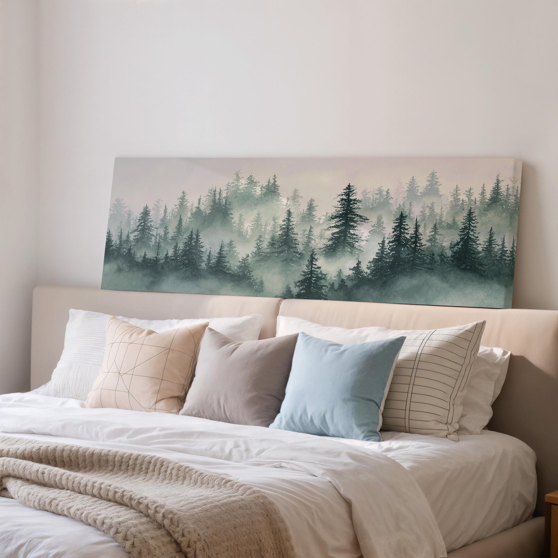 a bedroom with a large bed adorned with white sheets and a blue pillow. Above the bed, there is a large canvas print depicting a forest scene with misty trees.