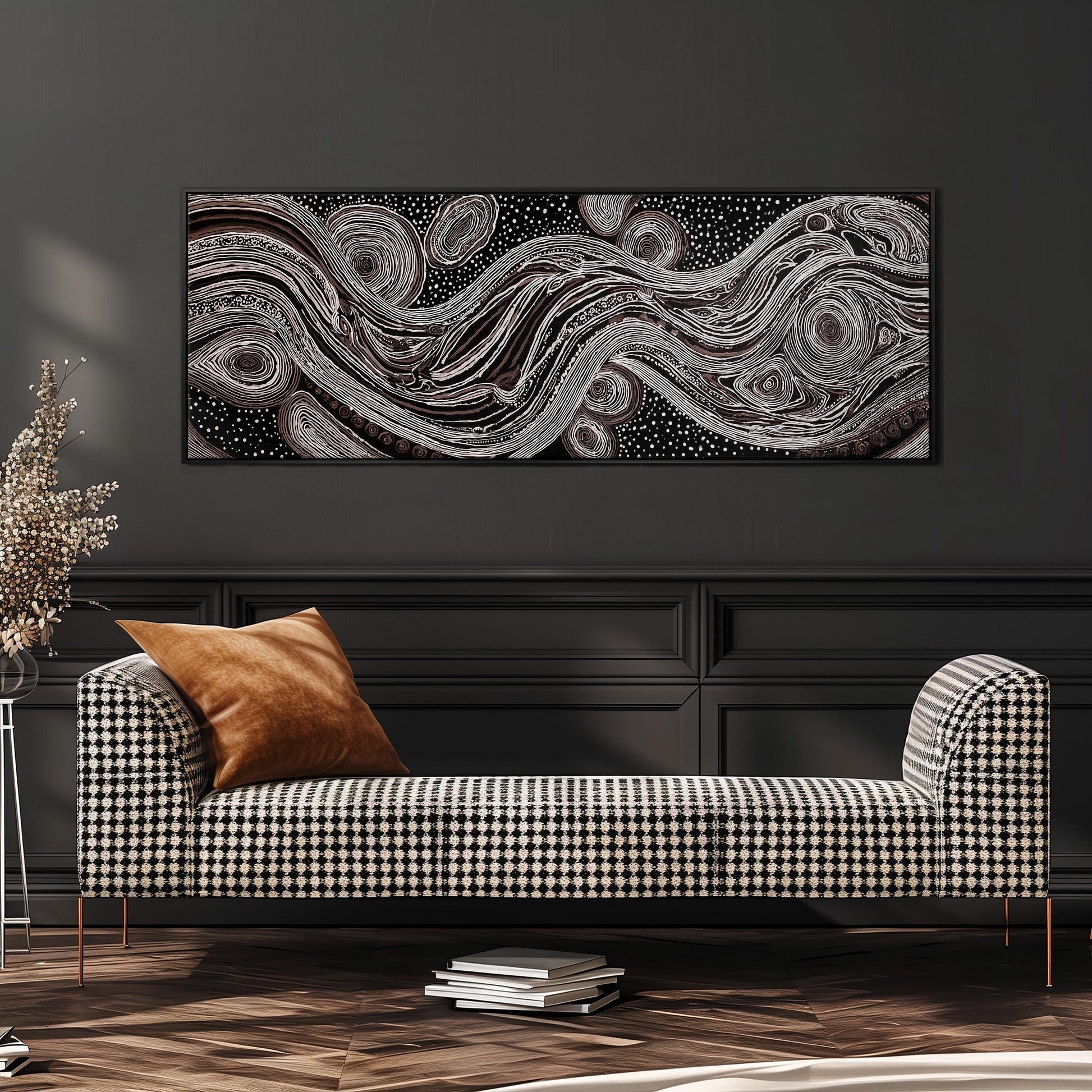 a modern living room with a black and white checkered sofa, a stack of books, and a large abstract painting hanging on the wall above the sofa.