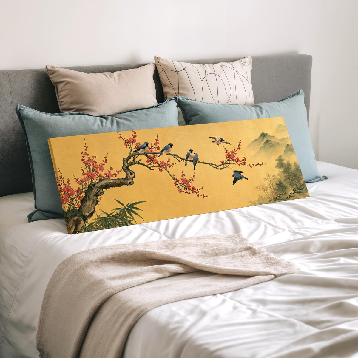 Birds on a plum blossom branch on gold wide panoramic canvas print laid on a bed to show its size