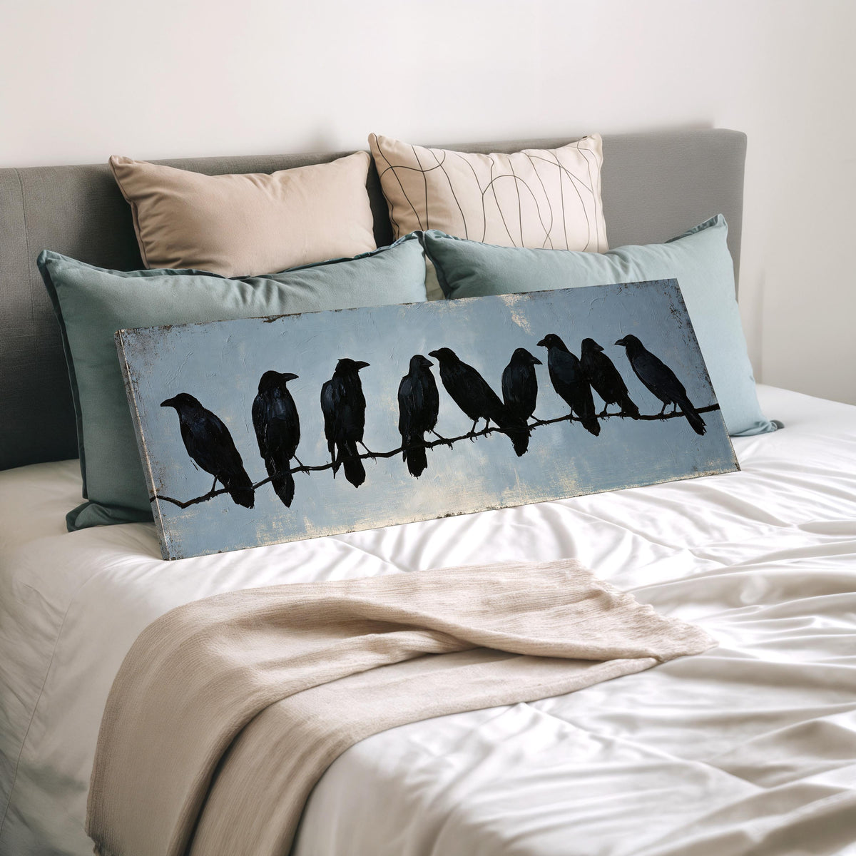 Crows gathered on a branch wide panoramic canvas print laid on a bed to show its size