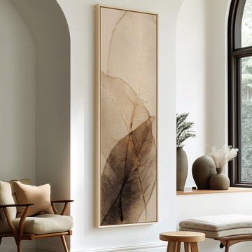 a minimalist living room with a large framed artwork of leafy leaves on the wall, a wooden chair, a small table, and a window with a plant on the sill.