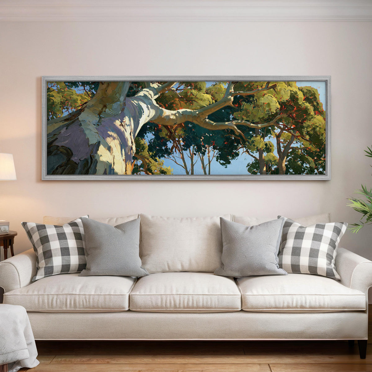Sunlit eucalyptus trunk and branches panoramic canvas print above a white sofa in a bright living room