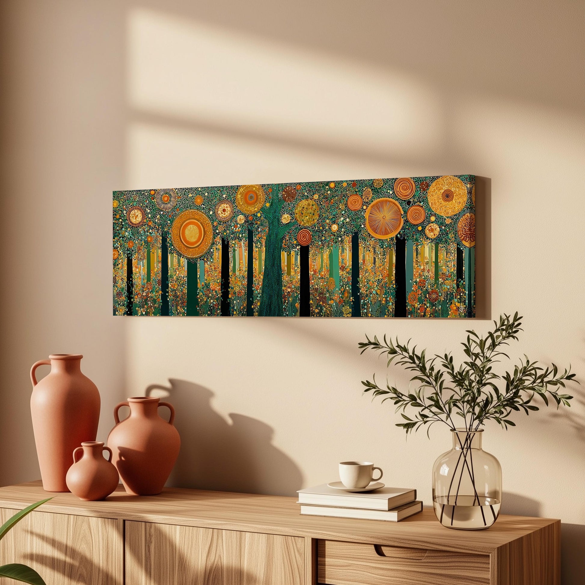a wooden cabinet with a vase of greenery, a stack of books, and a painting of a forest scene hanging on the wall above it.