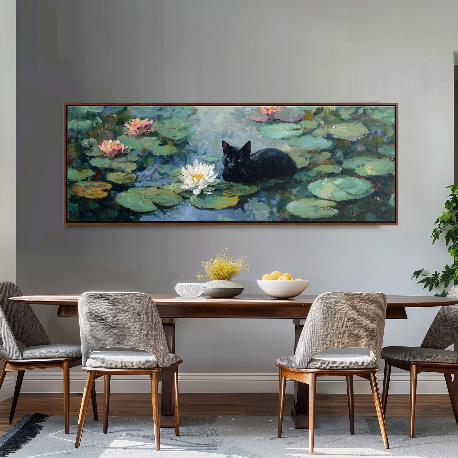 a large painting of a black cat sitting on a lily pad in a pond, surrounded by lily pads and flowers. The painting is hung on a wall above a wooden dining table with four chairs. The table is set with a bowl of fruit and a vase of flowers, creating a cozy and inviting atmosphere.