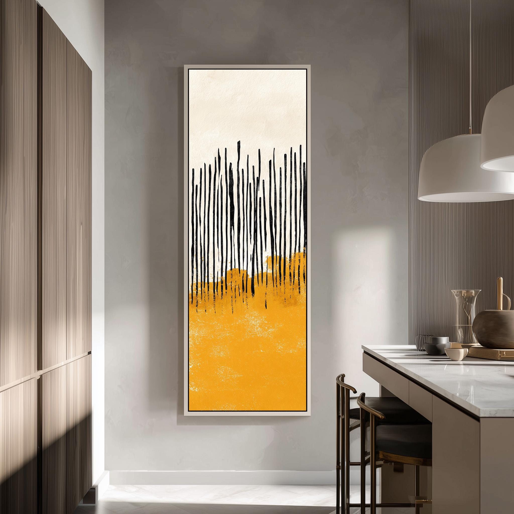 a modern kitchen with a large abstract painting hanging on the wall. The painting has a striking yellow and black color scheme, with vertical lines creating a sense of movement and energy. The kitchen is well-lit, with a pendant light hanging above the countertop and a wooden cabinet visible in the background.
