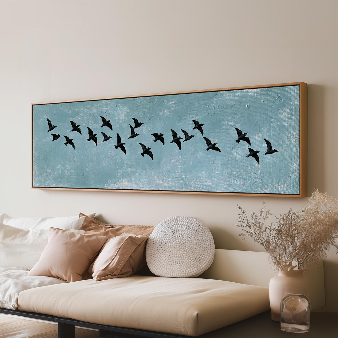 Flock of black birds on a teal sky long horizontal canvas print above a sofa in a living room