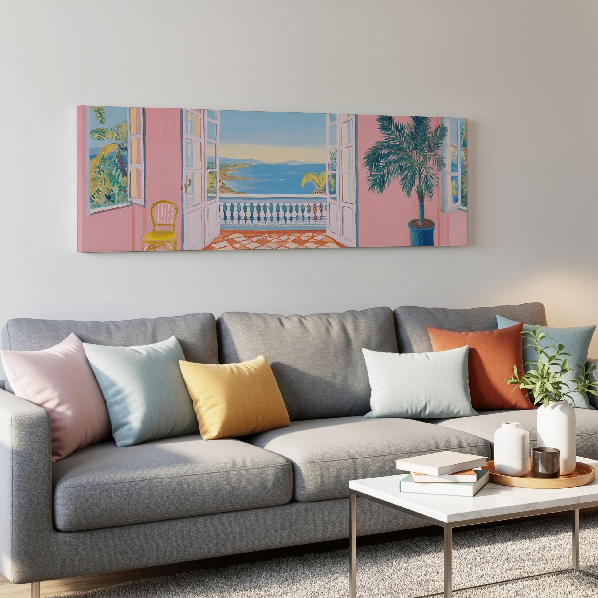 a cozy living room with a gray sofa adorned with colorful throw pillows, a white coffee table, and a painting of a balcony overlooking the ocean.