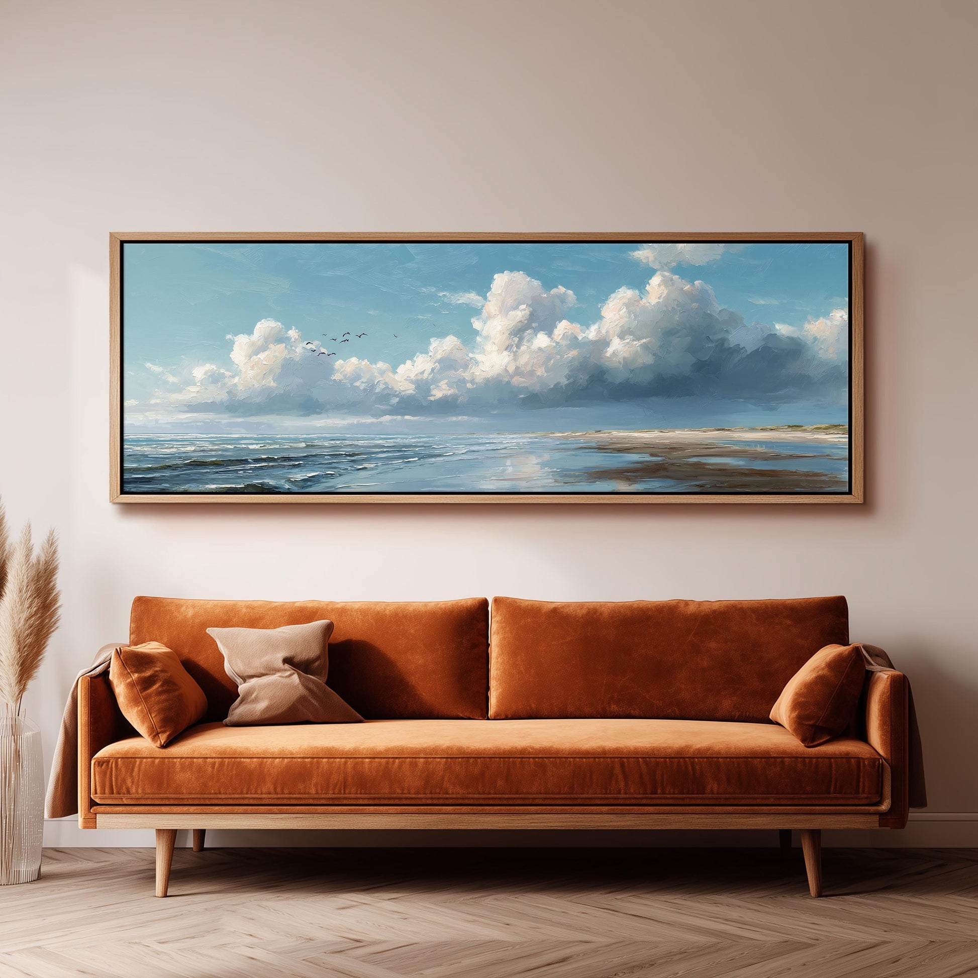 a large painting of a serene landscape hanging on a wall above a brown sofa with orange cushions.