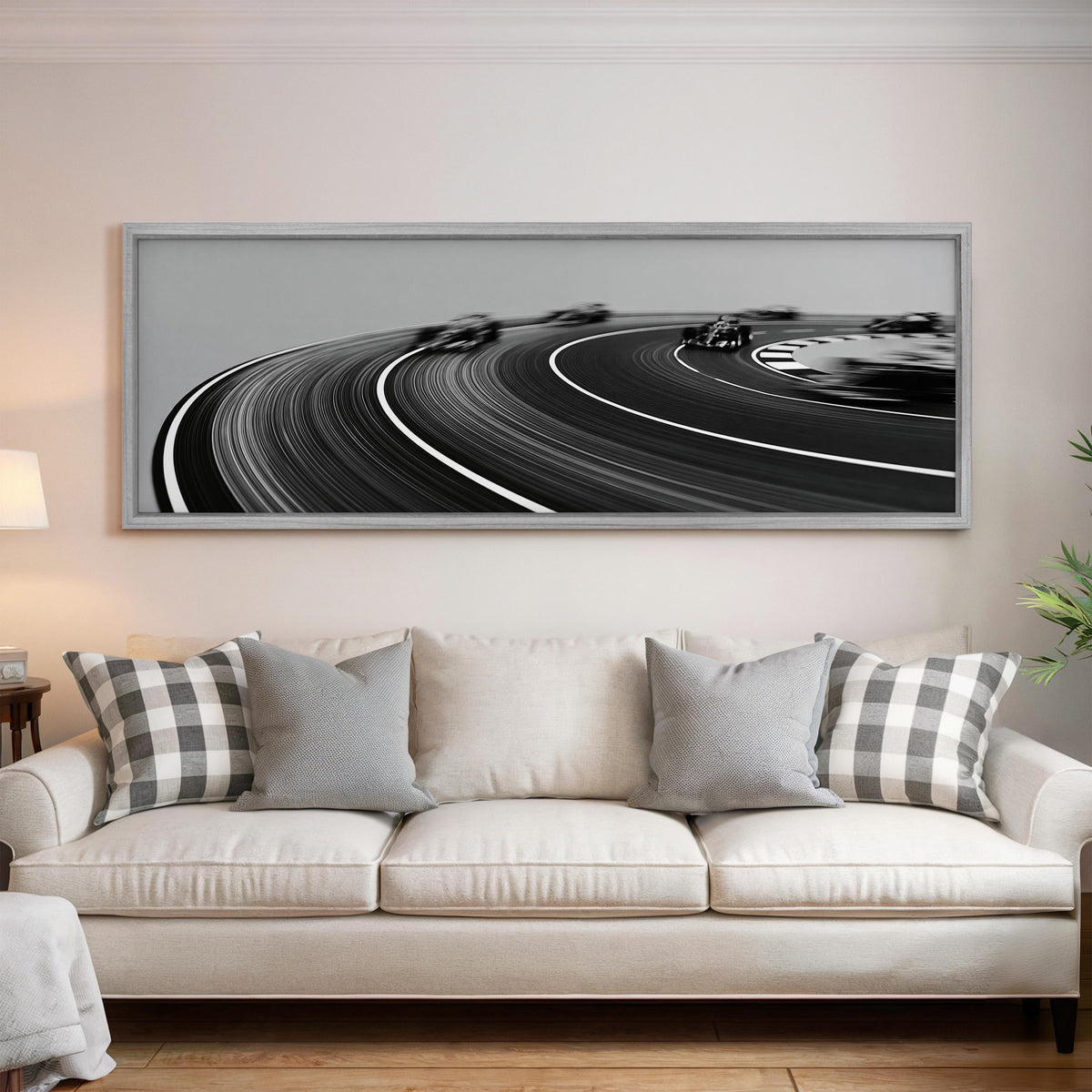 Race cars sweeping around a curve in black and white panoramic canvas print above a white sofa in a bright living room