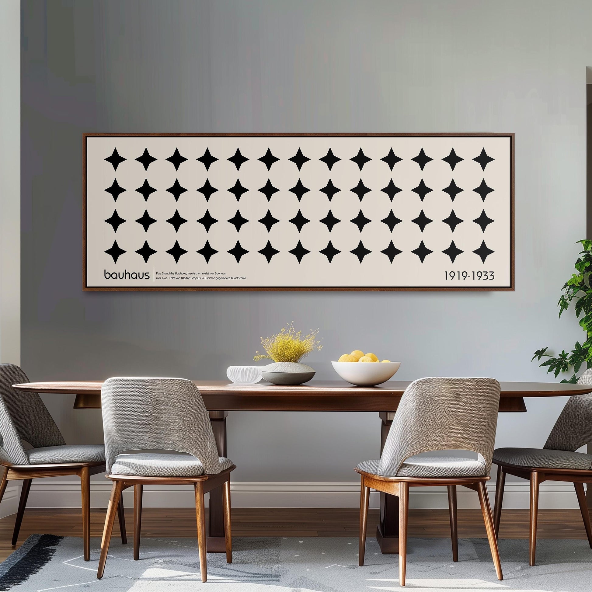a dining room with a wooden table and four chairs, a large framed poster on the wall above the table, and a bowl of fruit on the table.
