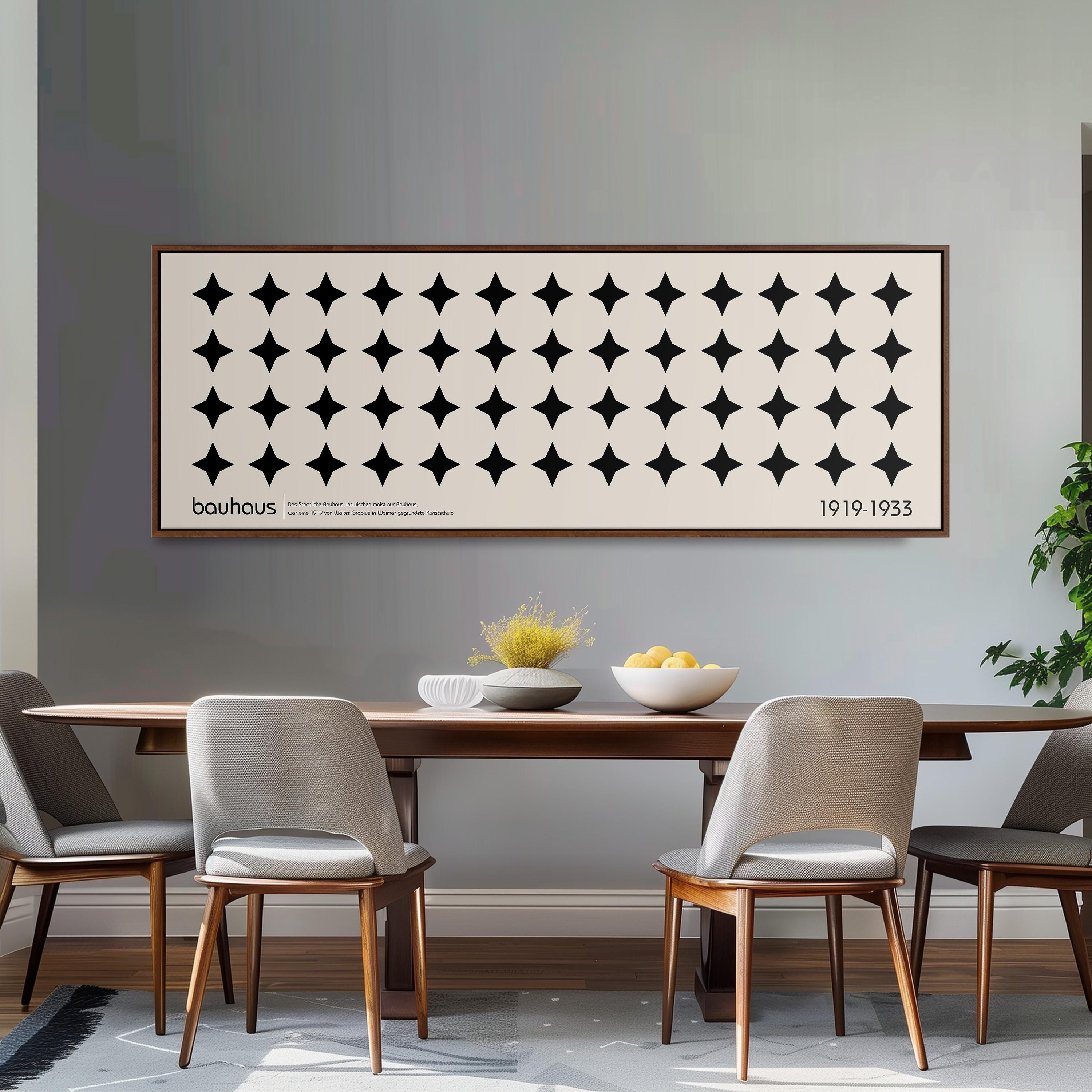 a dining room with a wooden table and four chairs, a large framed poster on the wall above the table, and a bowl of fruit on the table.
