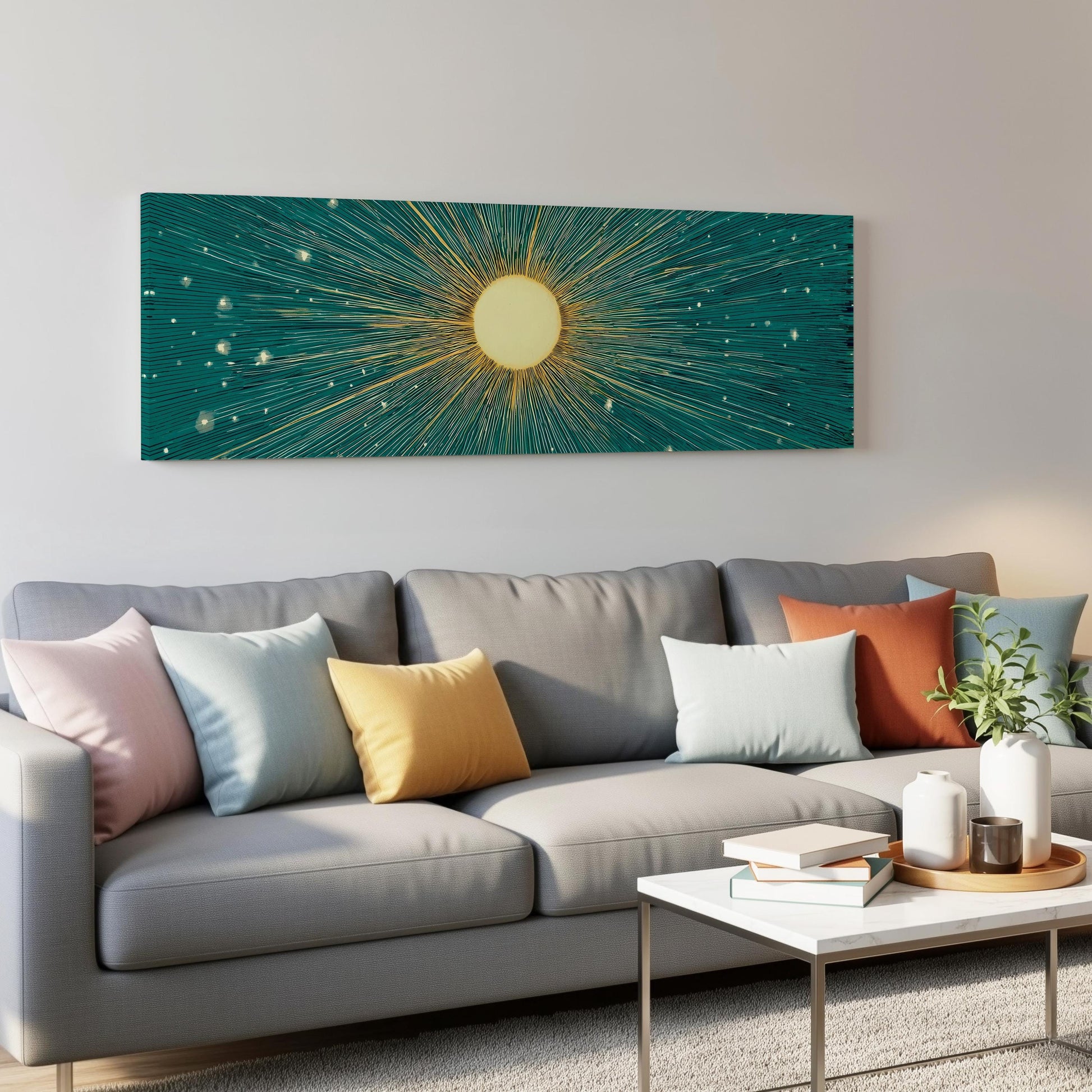 a modern living room with a gray sofa adorned with colorful throw pillows. Above the sofa, a large abstract painting of a sun with rays radiating from it is displayed on the wall. The room also includes a coffee table with books and a plant, creating a cozy and inviting atmosphere.