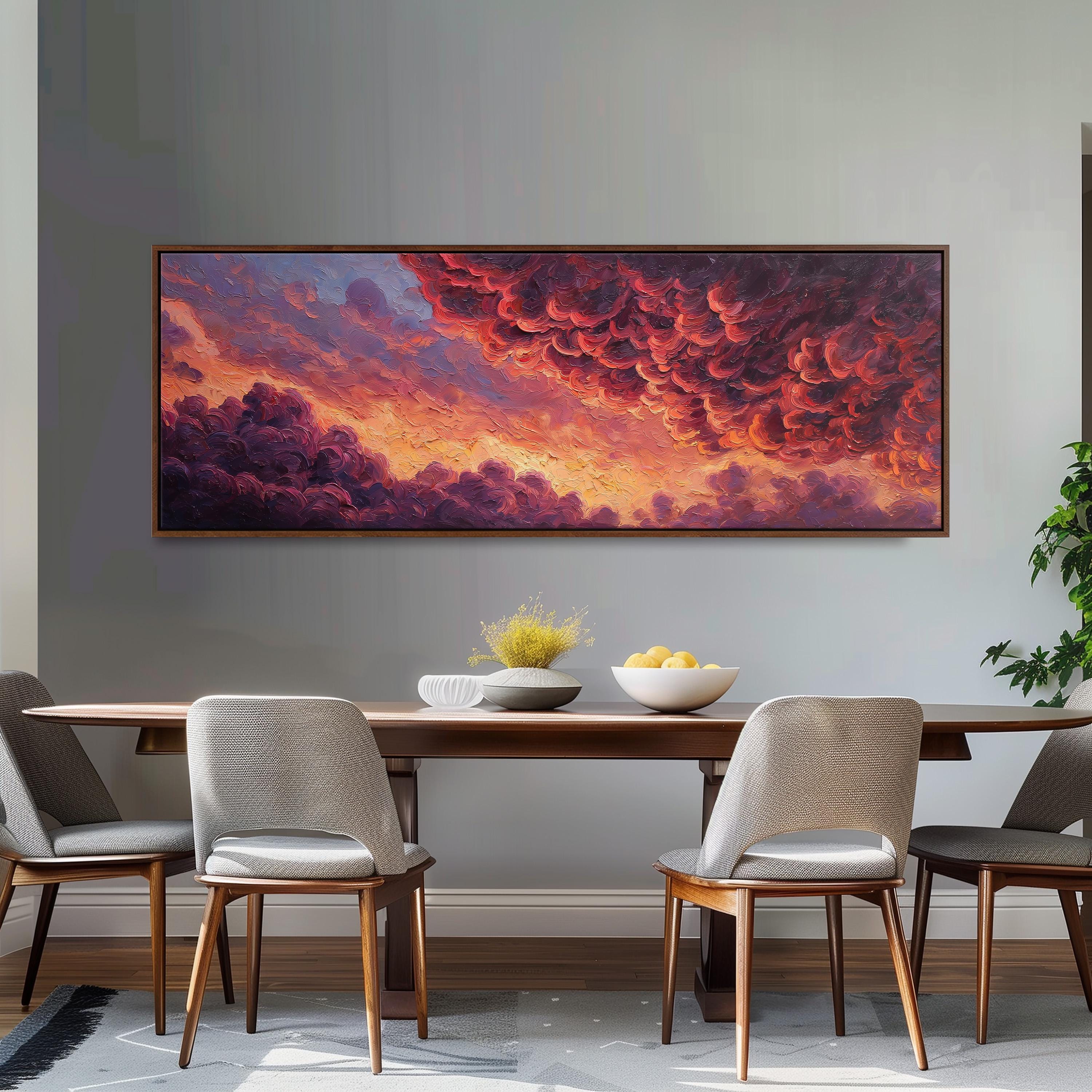 a dining room with a large painting of a vibrant sunset over a cloudy sky hanging on the wall above a wooden dining table with four chairs. The table is set with a bowl of fruit and a vase of flowers, creating a cozy and inviting atmosphere.
