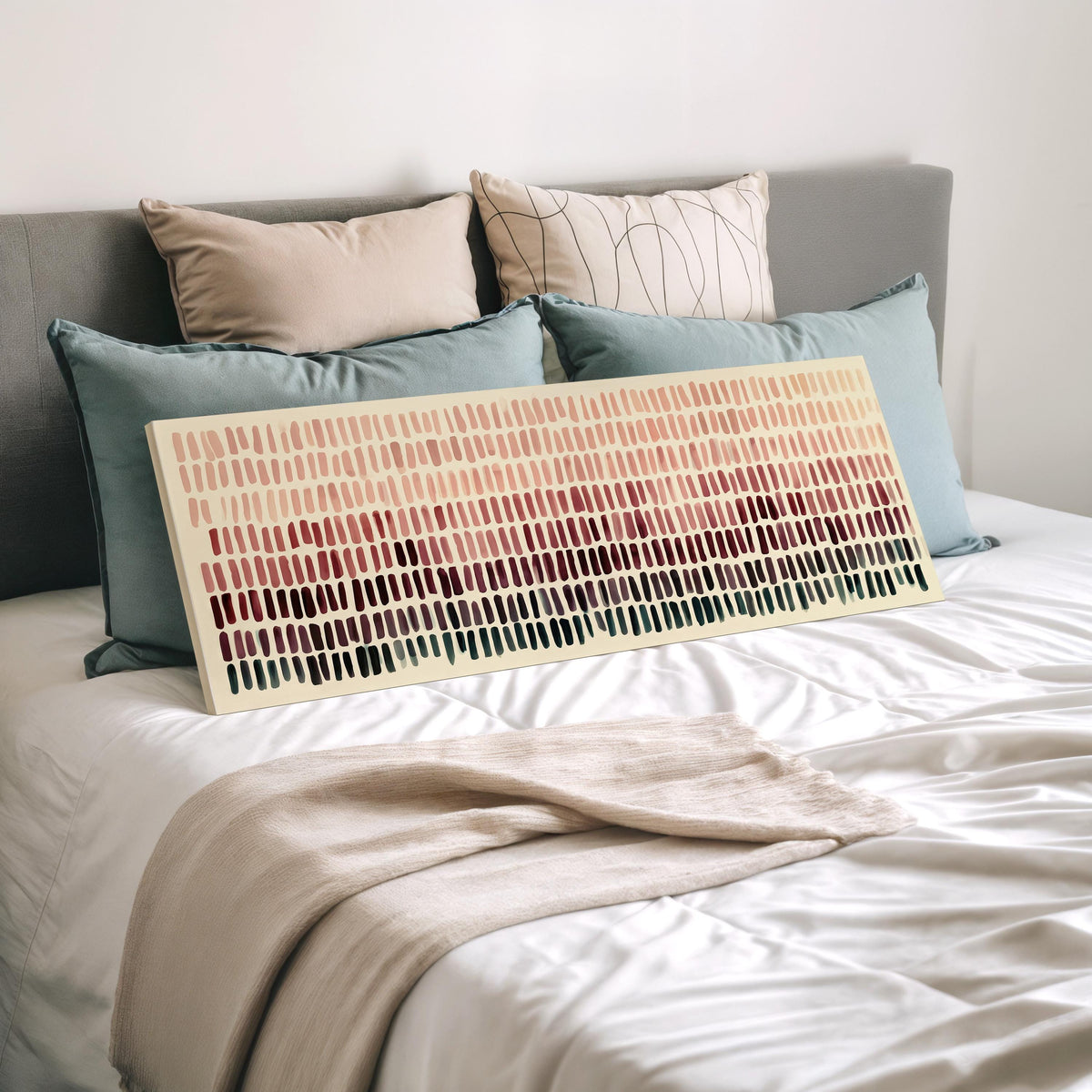 Brushmarks fading from blush to deep maroon wide panoramic canvas print laid on a bed to show its size