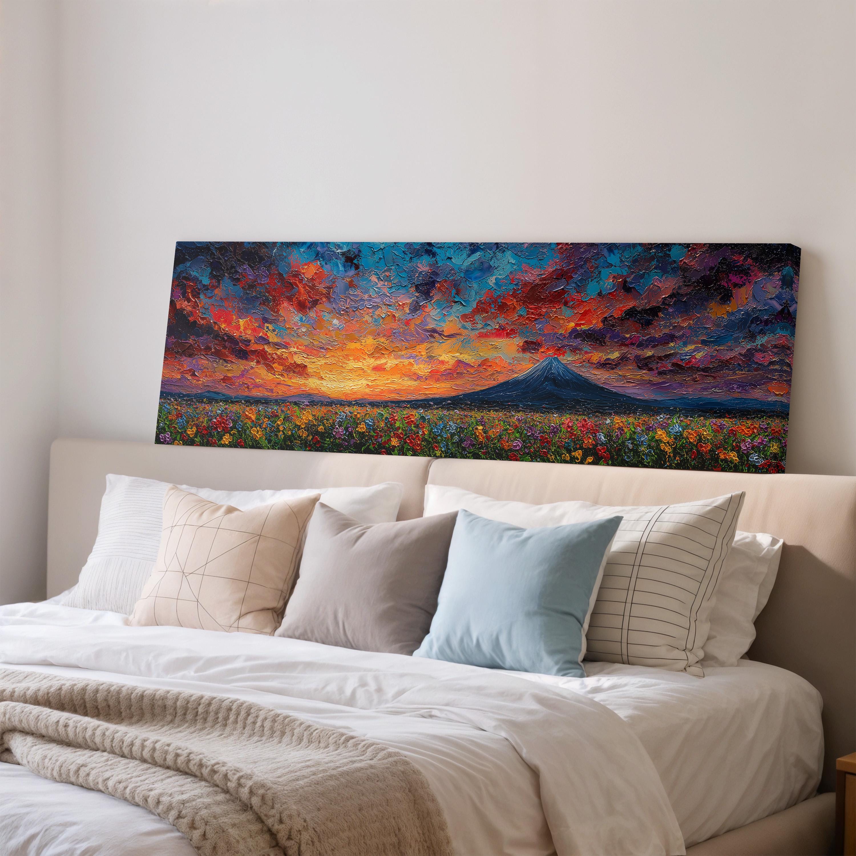 a large, colorful painting of a sunset over a mountain landscape, which is displayed on the wall above a bed with white bedding and pillows.