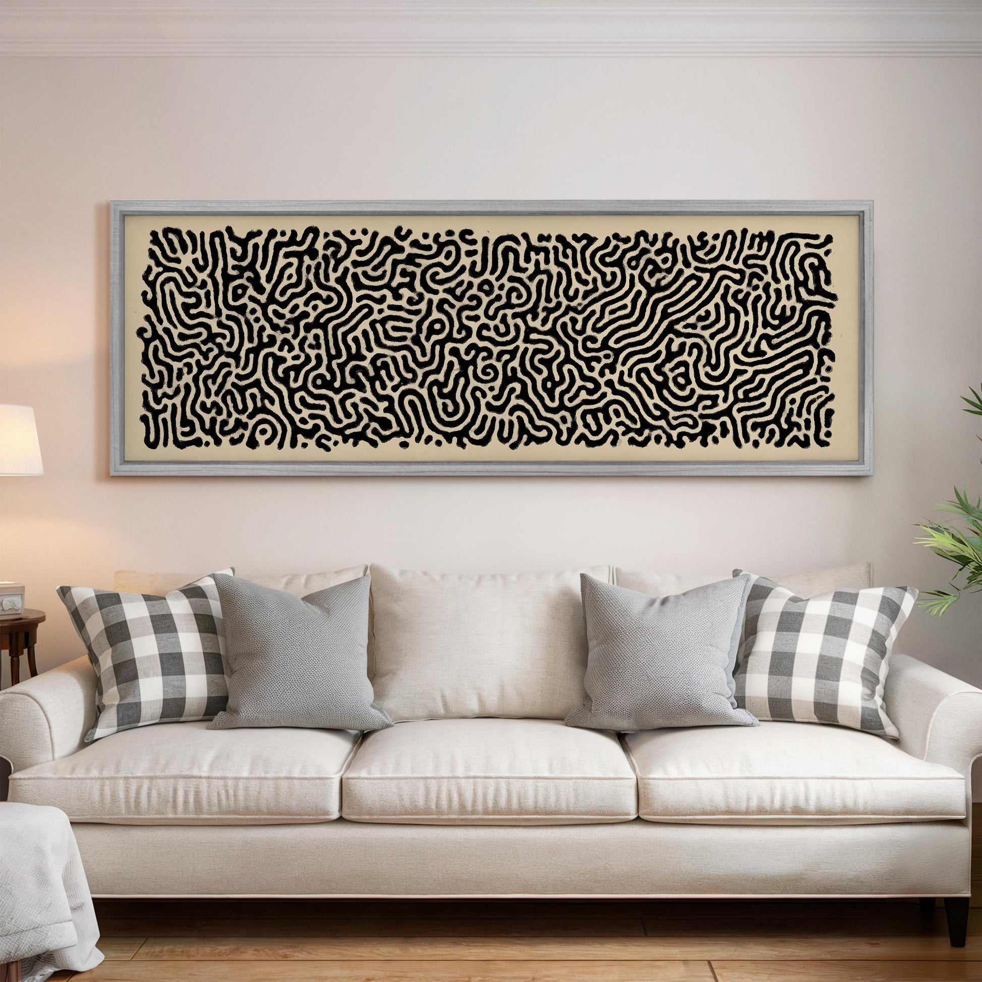 a large, abstract painting hanging on a wall above a white couch with gray and white plaid throw pillows.