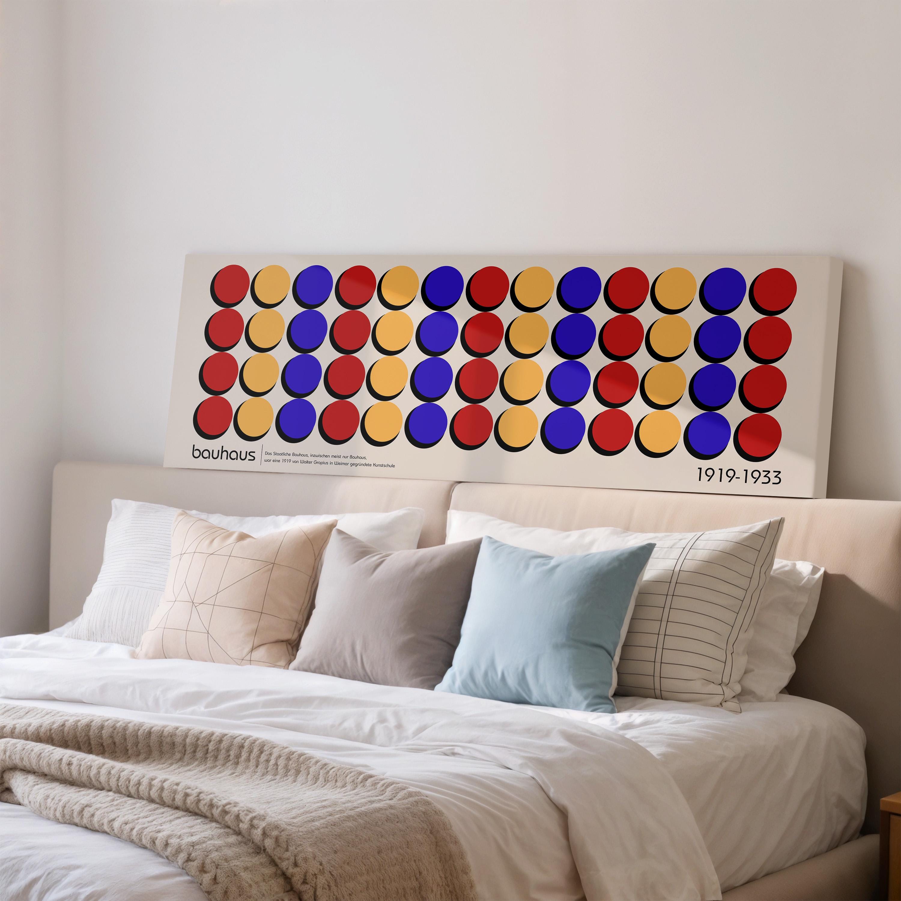 a large, colorful abstract painting hanging on a wall above a bed with white bedding.