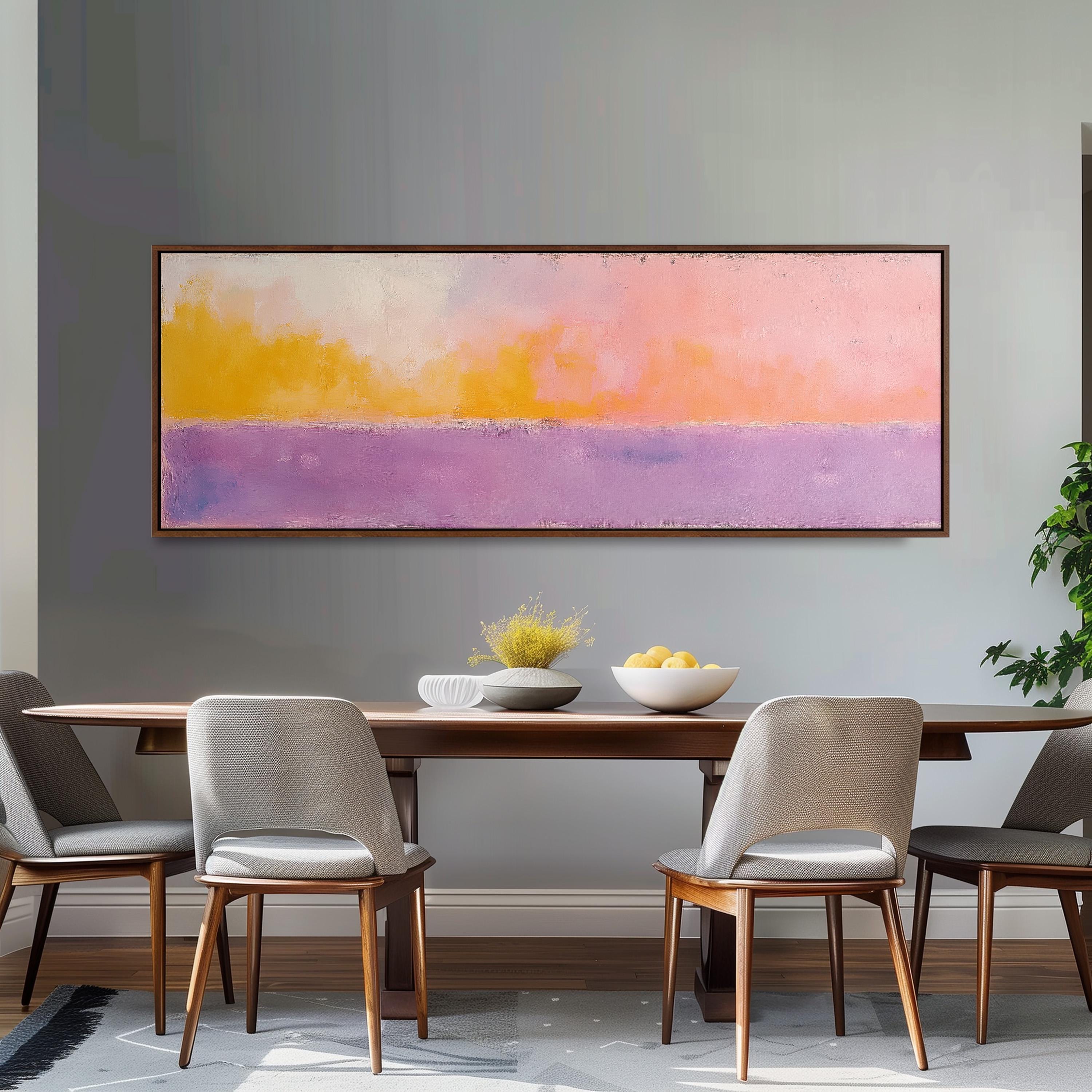a dining room with a wooden table and four chairs. Above the table, there is a large painting depicting a sunset with a gradient of colors. The painting is framed and hangs on the wall above the table.