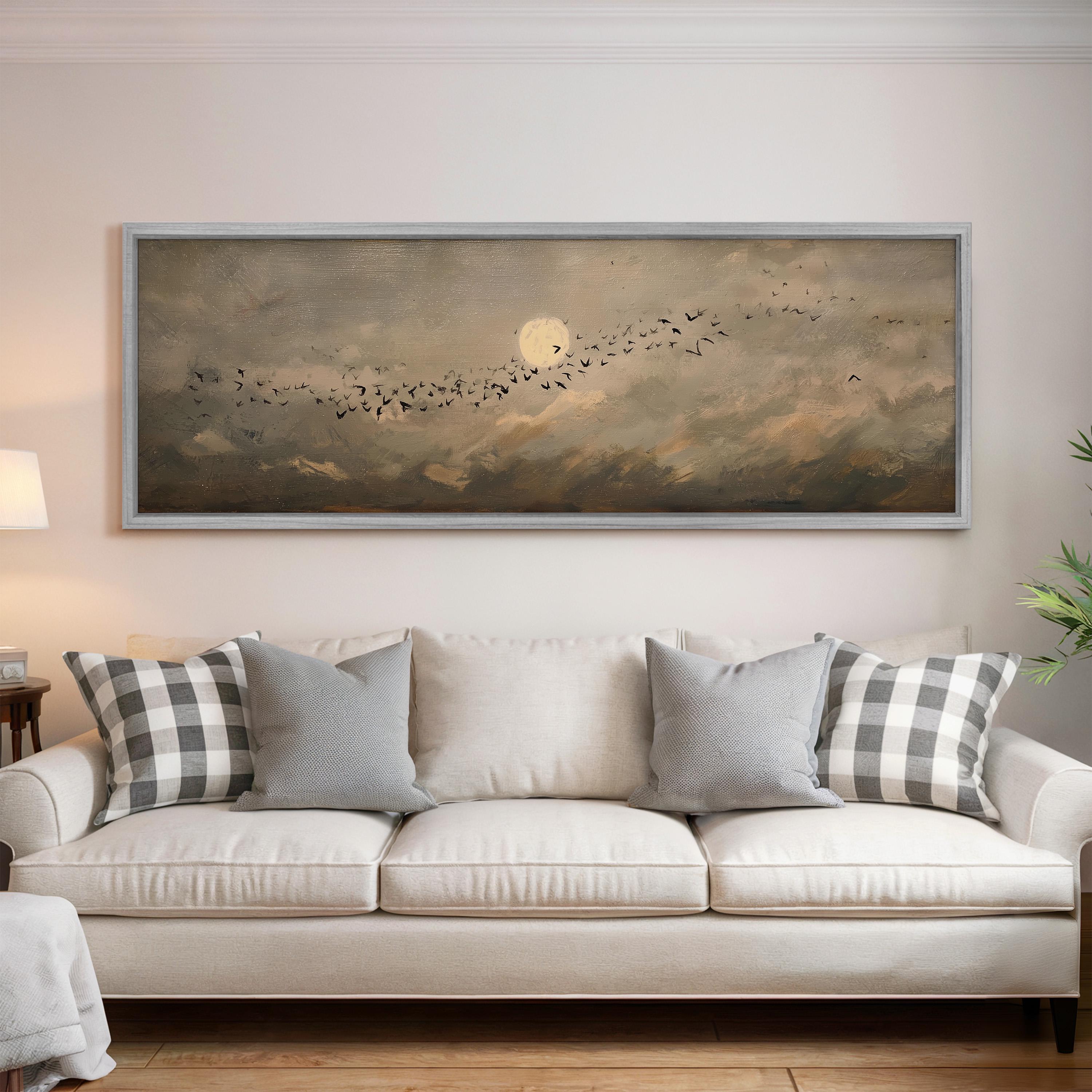 a large painting of a flock of birds flying over a cloudy sky, hanging on a wall above a white sofa with gray and white patterned pillows.