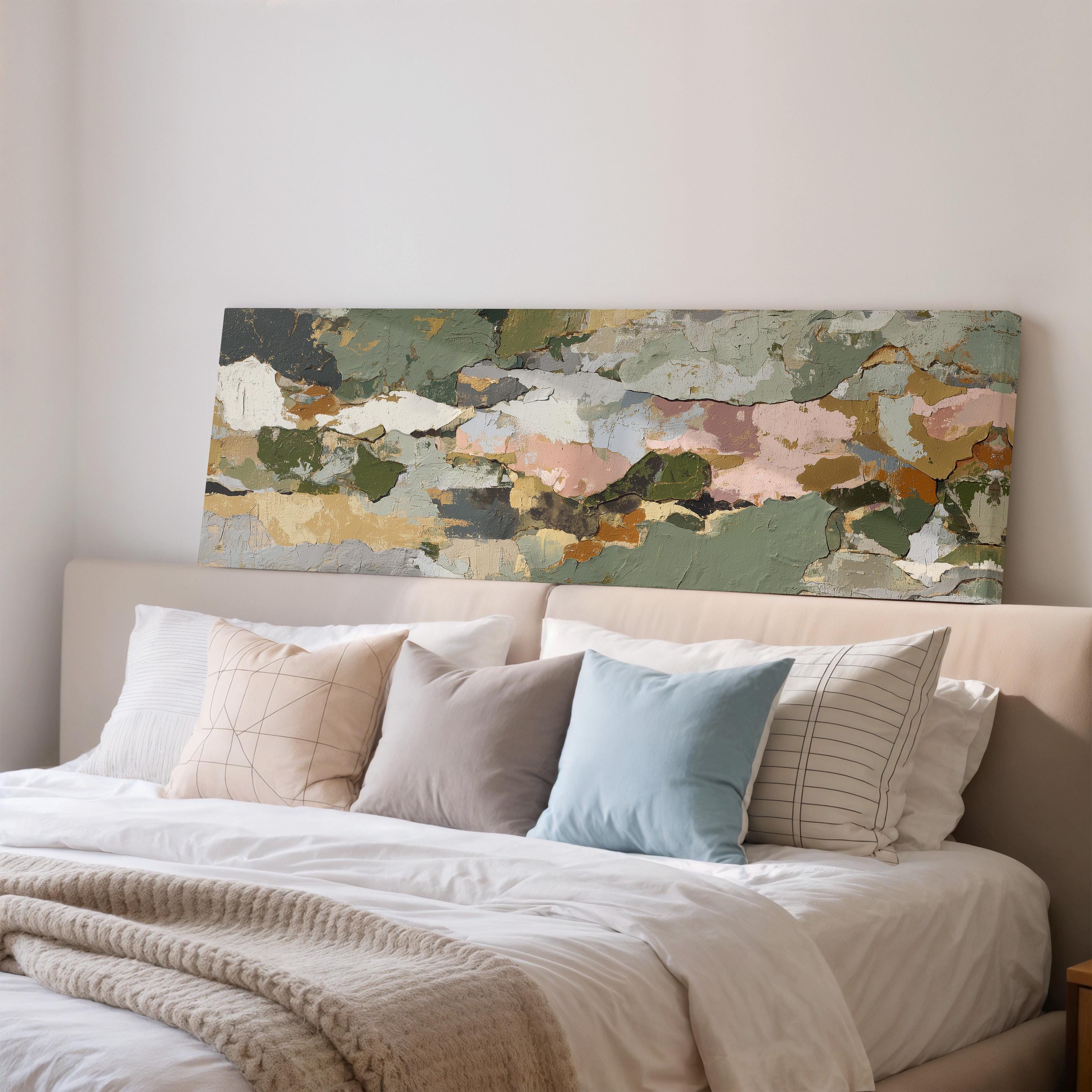 a large abstract painting hanging on a wall above a bed with white pillows and a gray blanket.