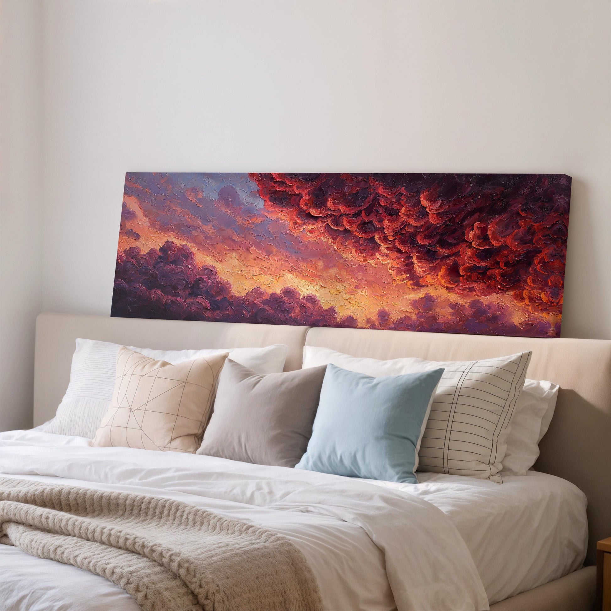 a large, colorful painting of a sunset over a field, hanging on a wall above a bed with white pillows and a gray blanket.