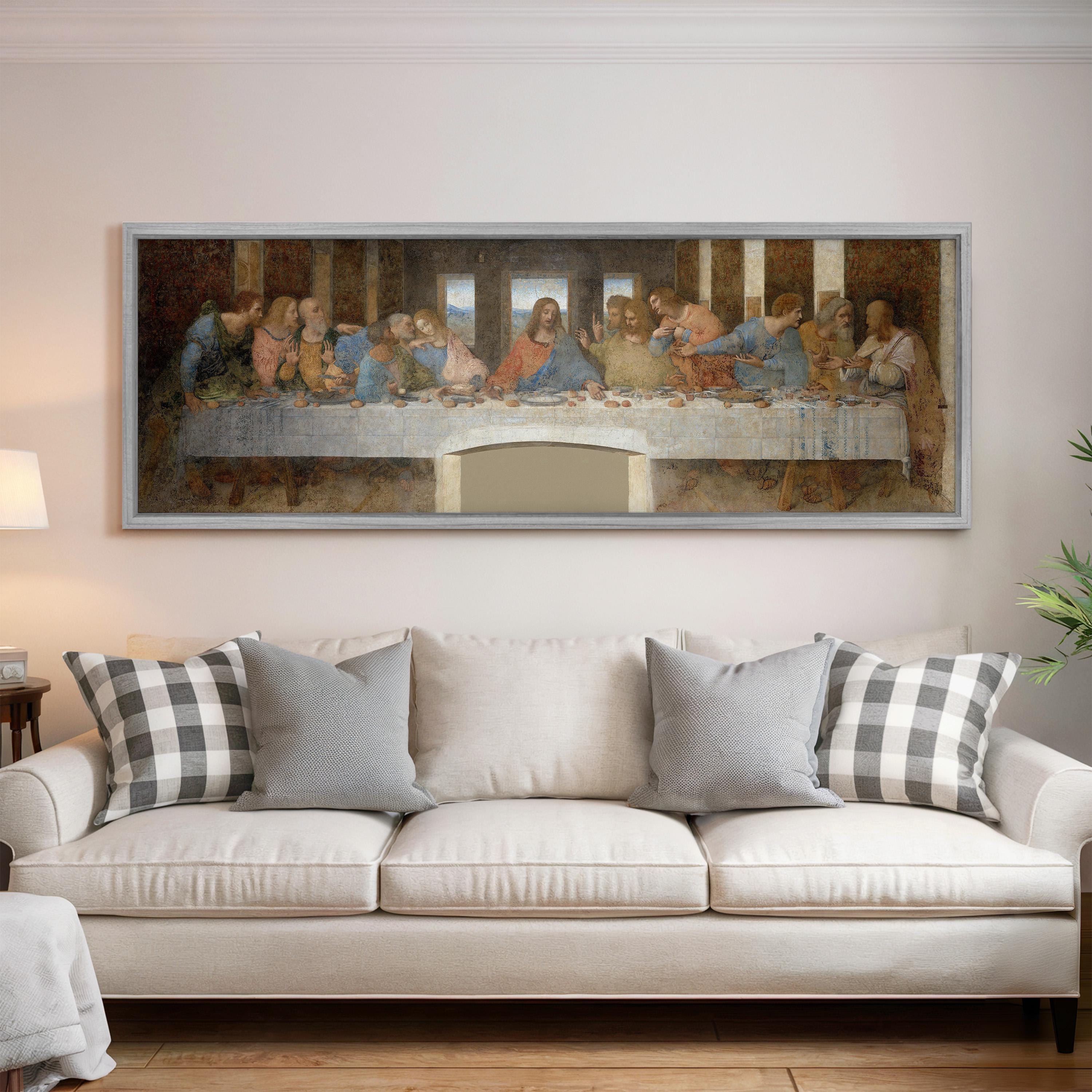a large painting of the Last Supper hanging on a wall above a white couch with pillows.